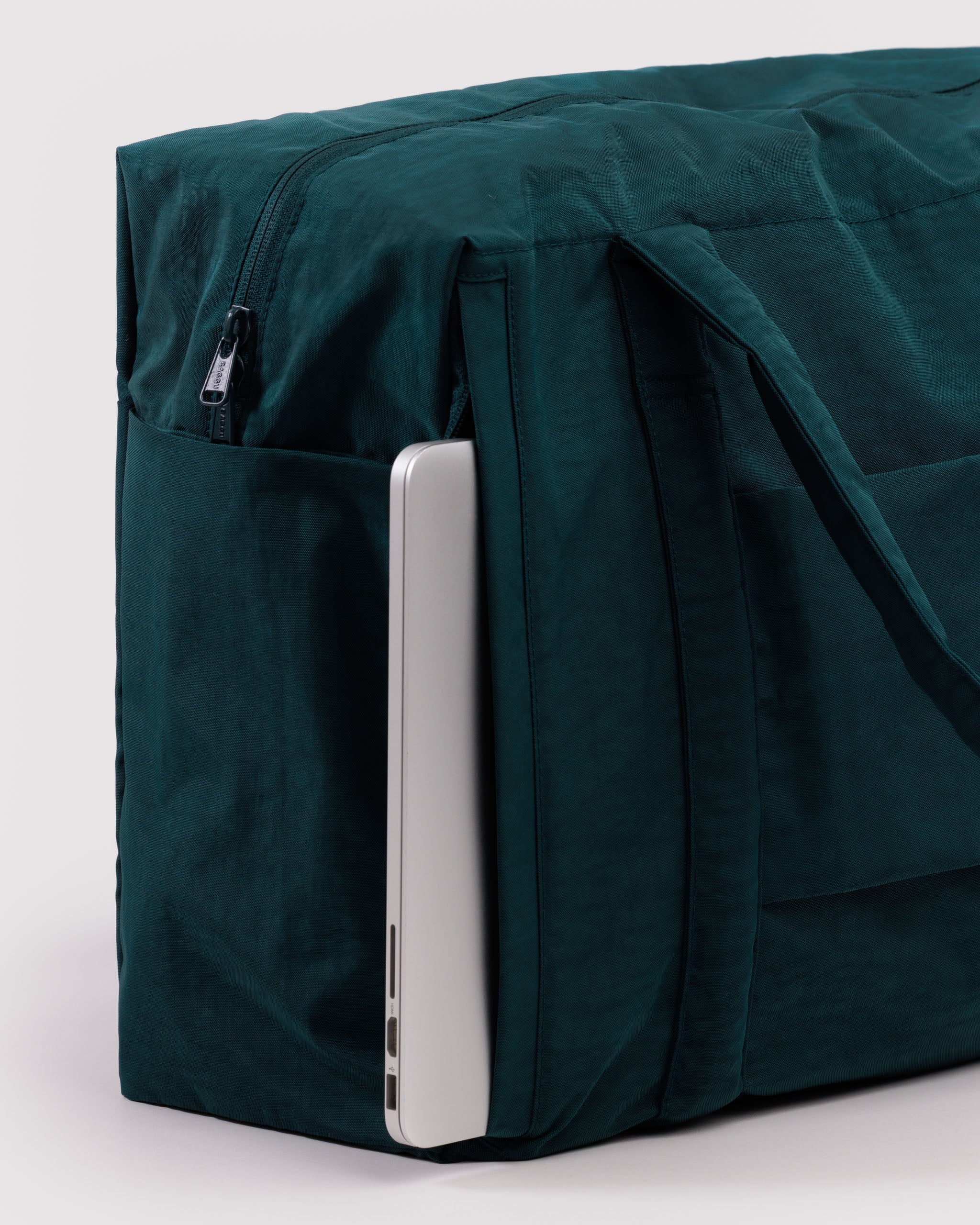 Green travel bag with a laptop sticking out of a side zip pocket.