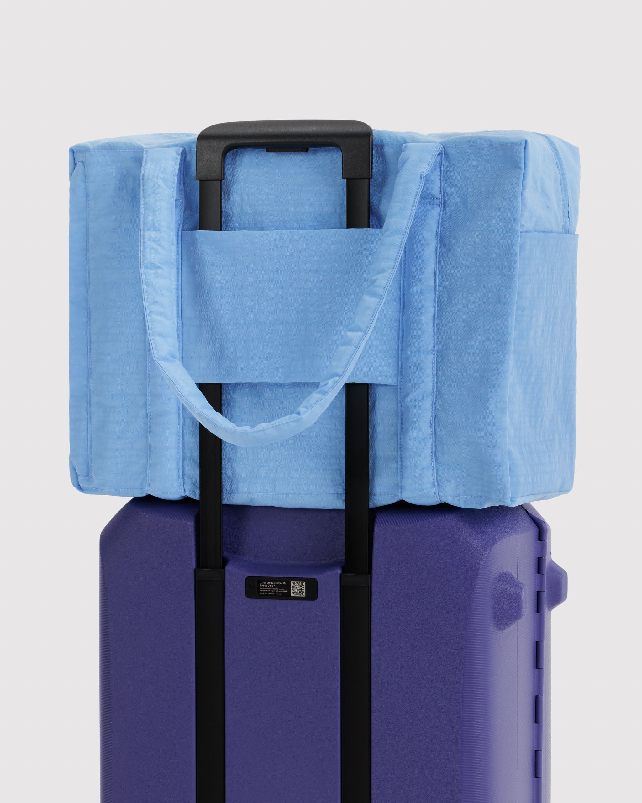 Blue duffle bag with luggage sleeve attached to suitcase