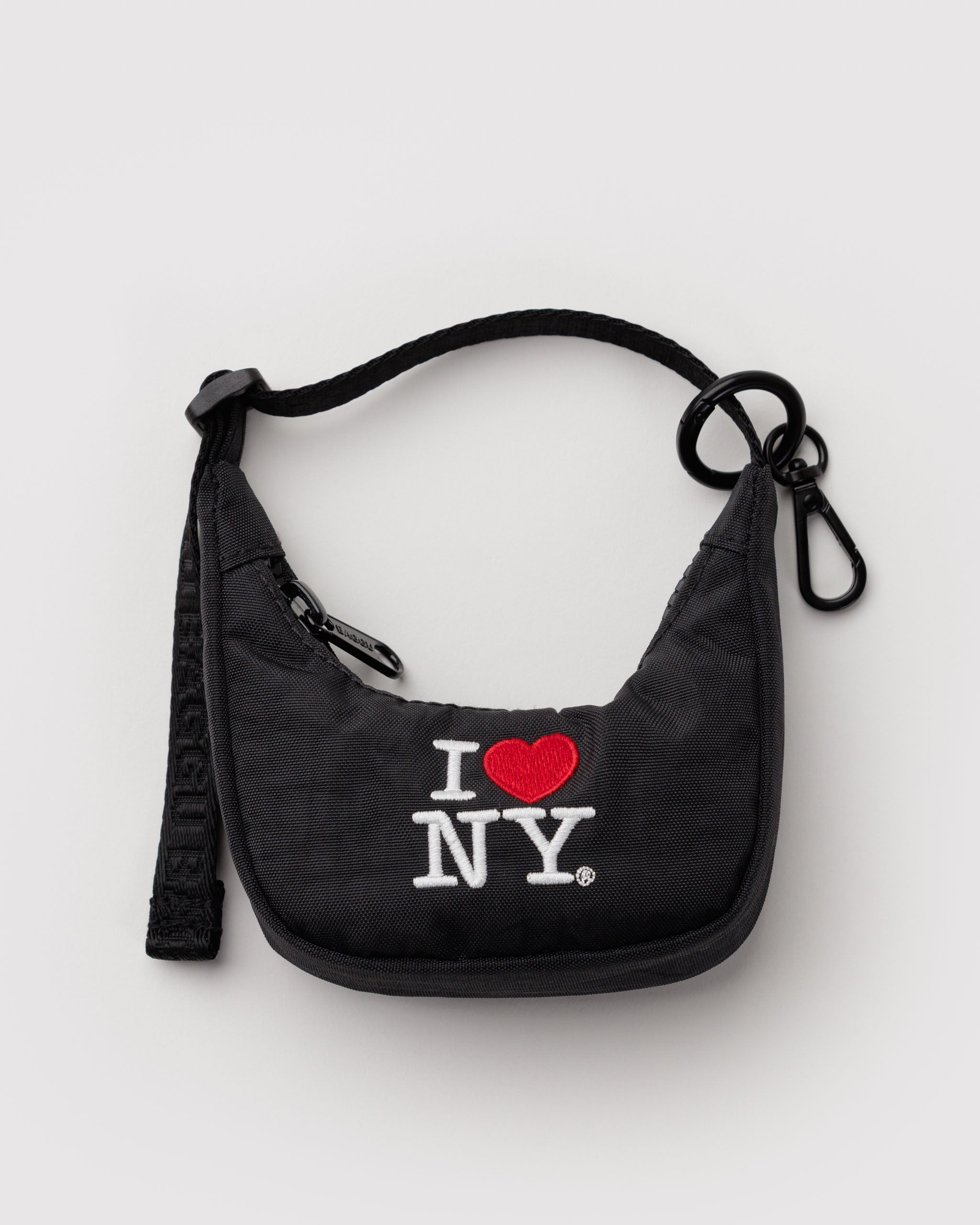 Black crescent bag charm with 'I ❤️ NY' text in red with adjustable strap and metal clip.