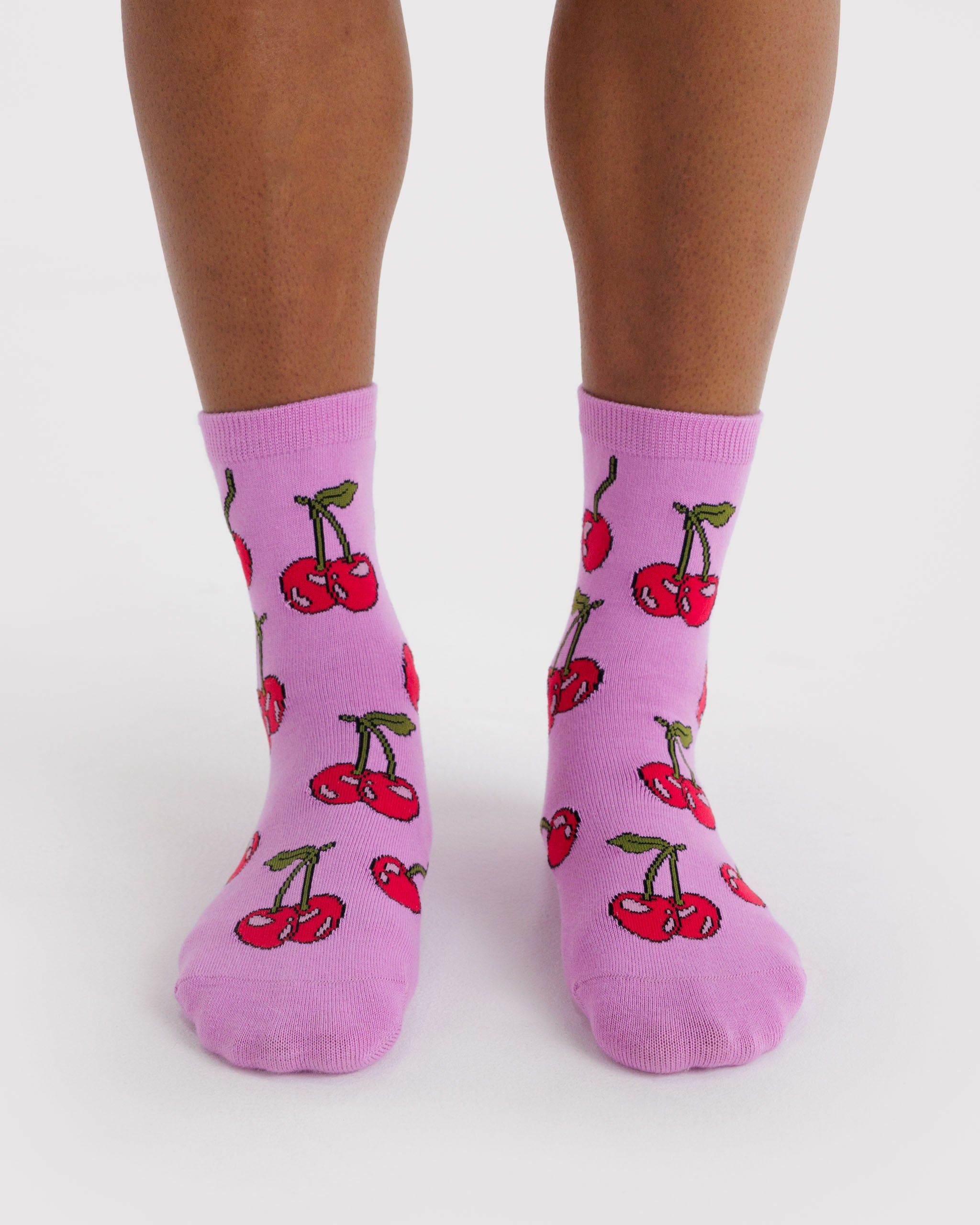 Person wearing pink socks with a cherry pattern.