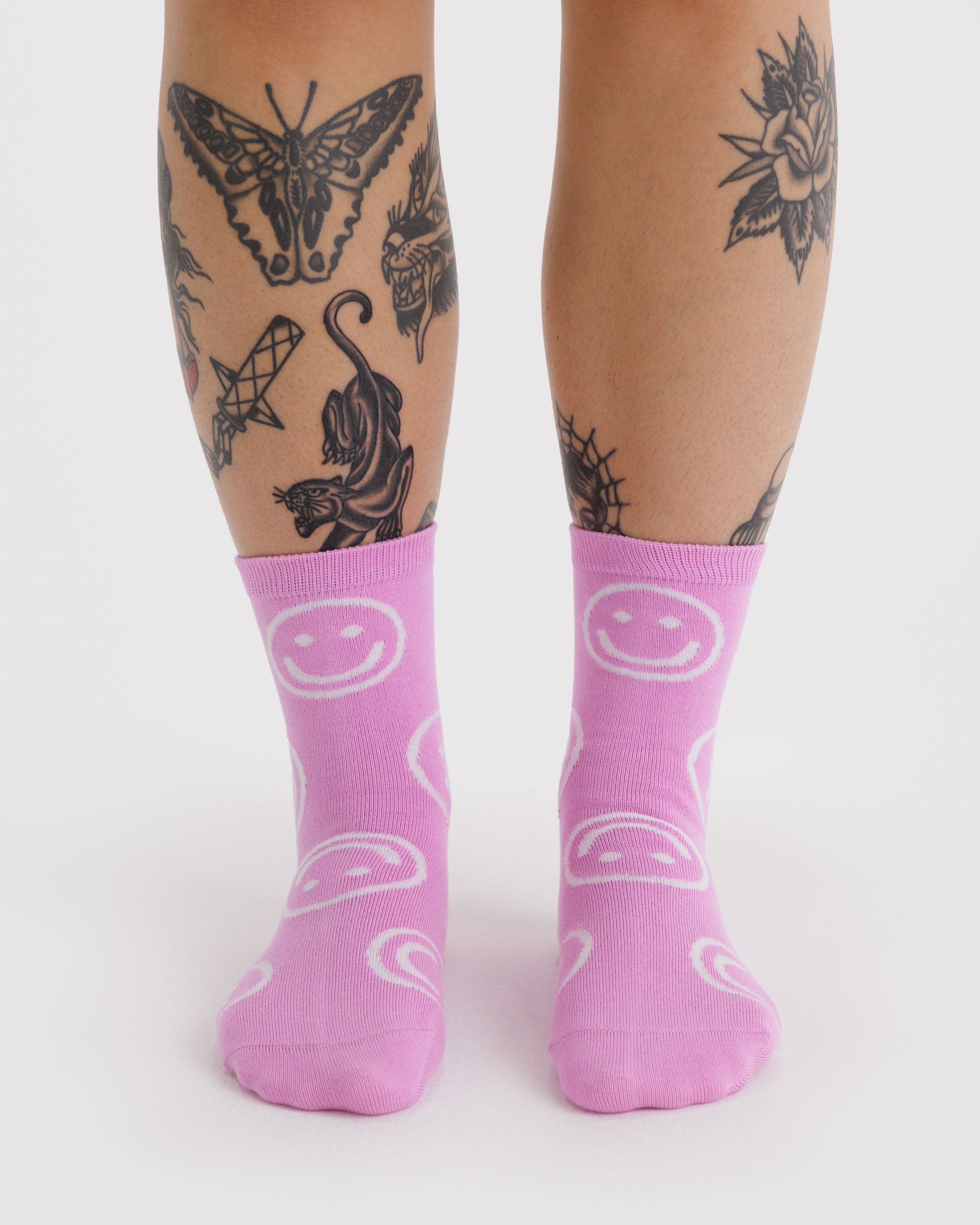 Person wearing pink socks with smiley face pattens.