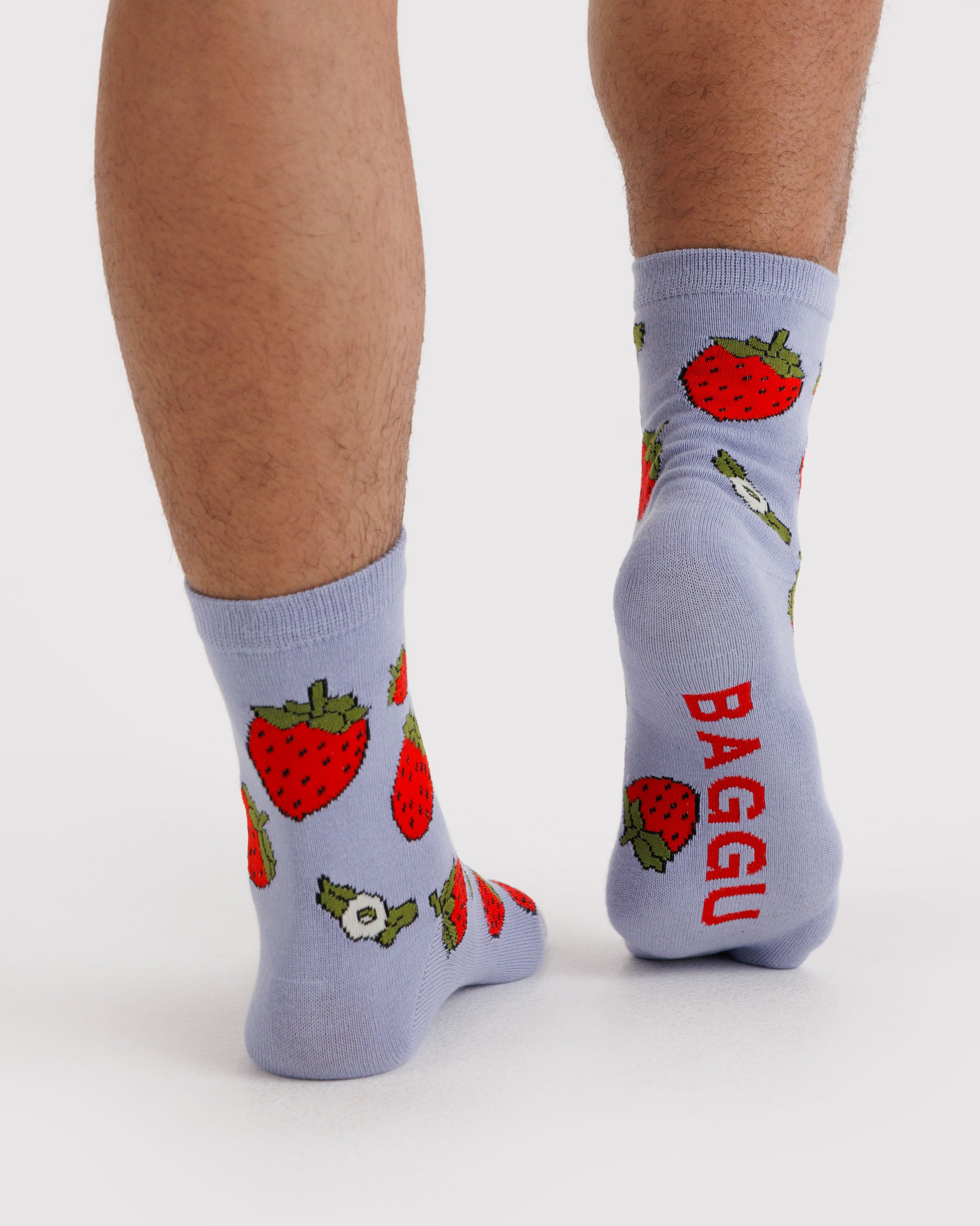 Person wearing light blue socks with strawberry pattern and 'BAGGU' branding on sole.