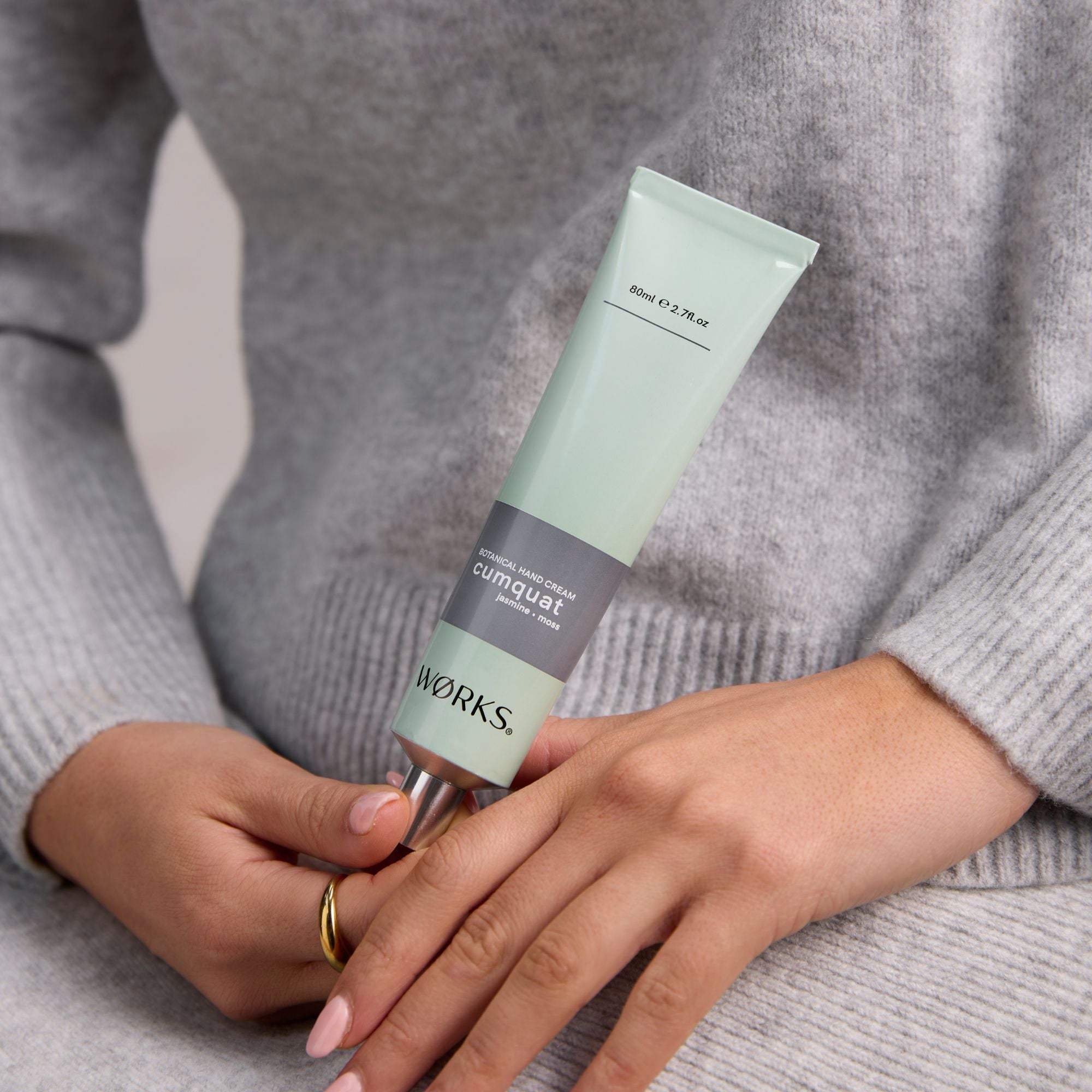 Person holding a green aluminium tube of cumquat Works hand cream.