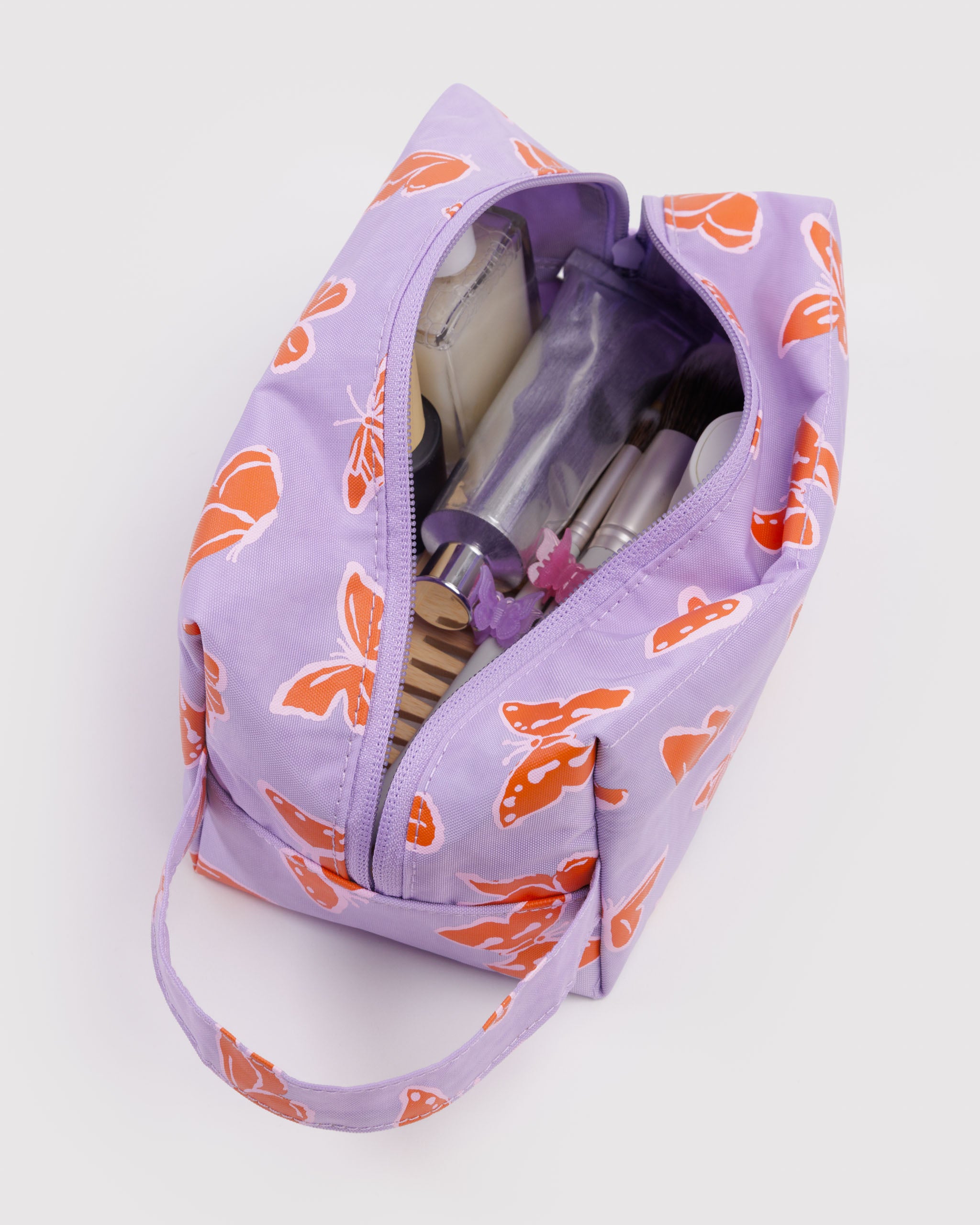 Purple makeup bag with orange floral pattern containing toiletry items.