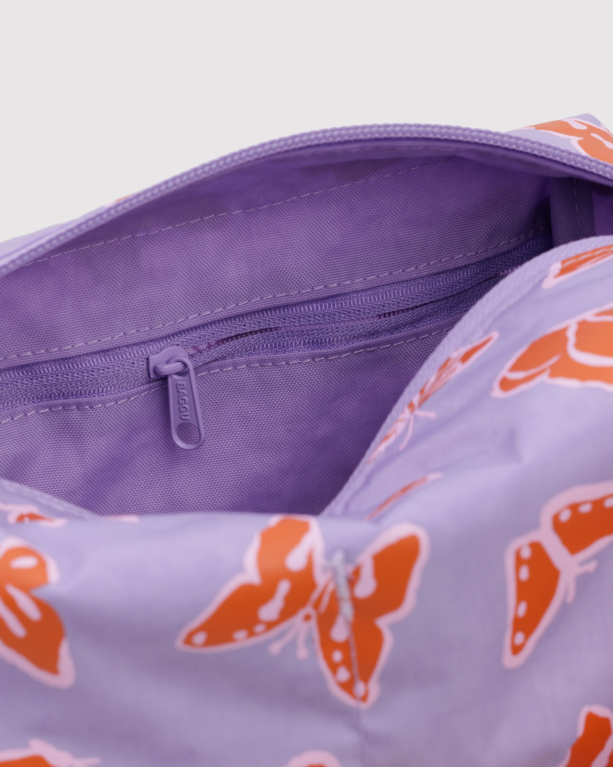 Close up of purple pouch with orange butterfly pattern and interior zip pocket.