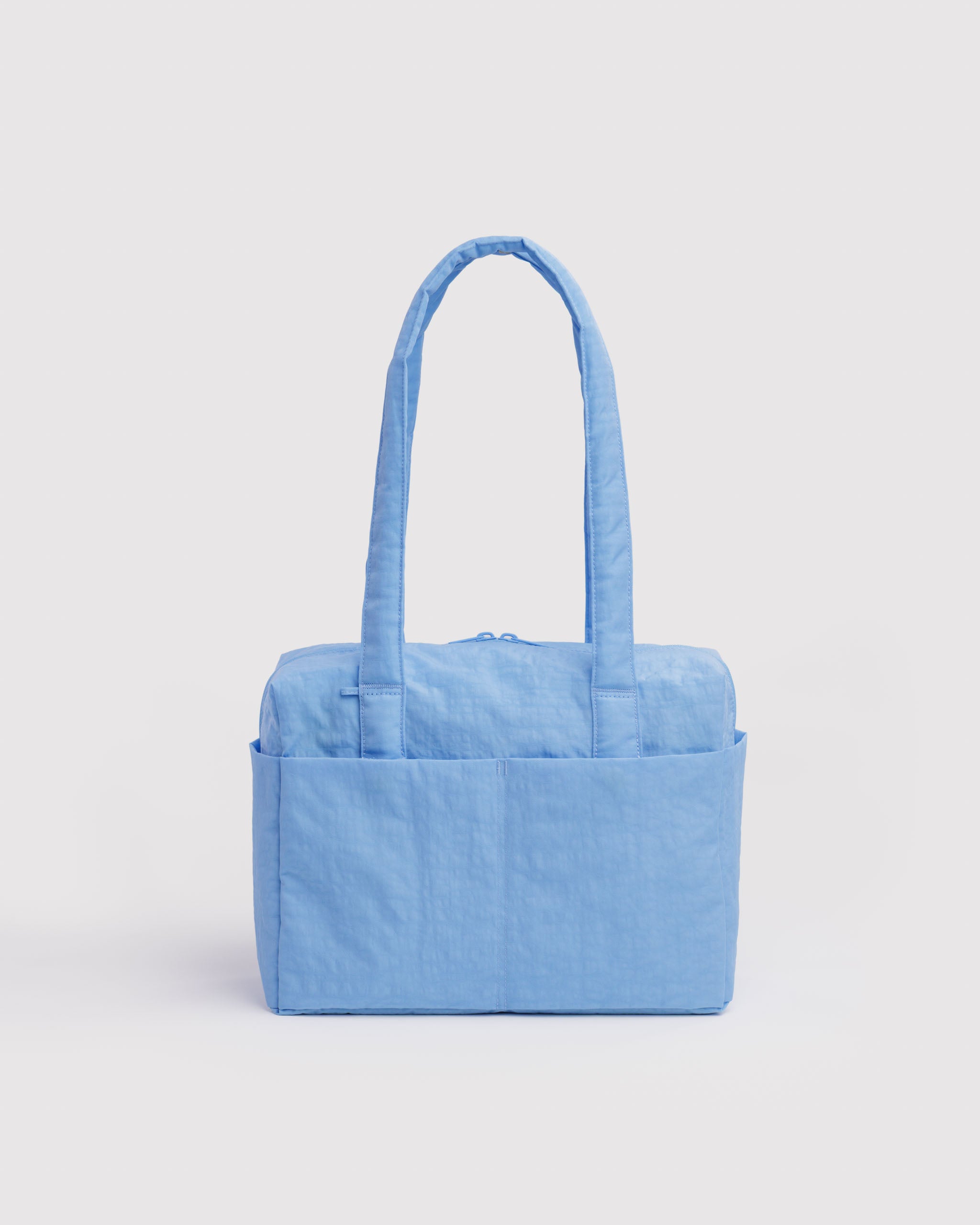 Light blue tote bag with external slip pockets and zip closure.
