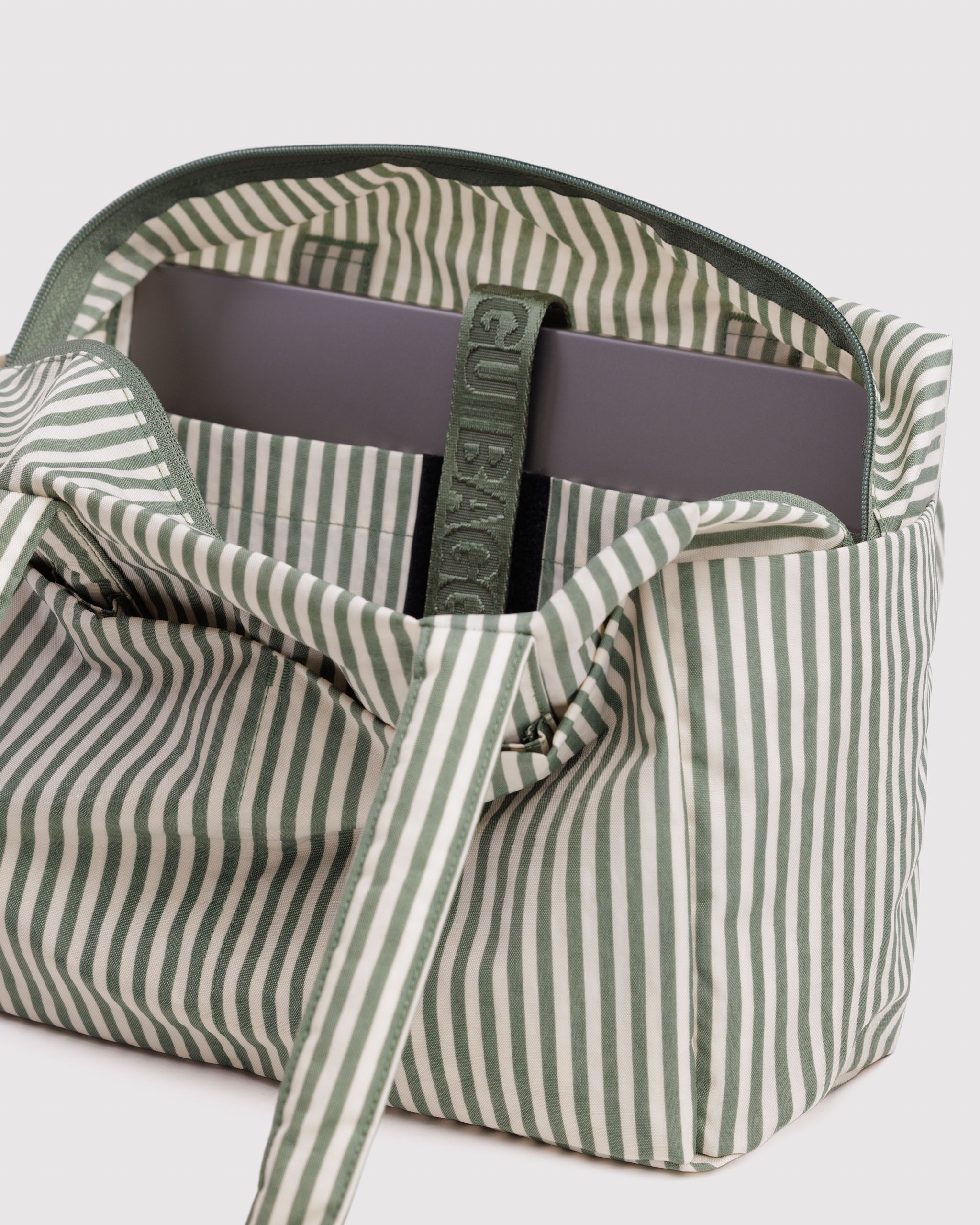 Green and white striped bag with a visible brand logo on velcro closure for internal laptop pocket