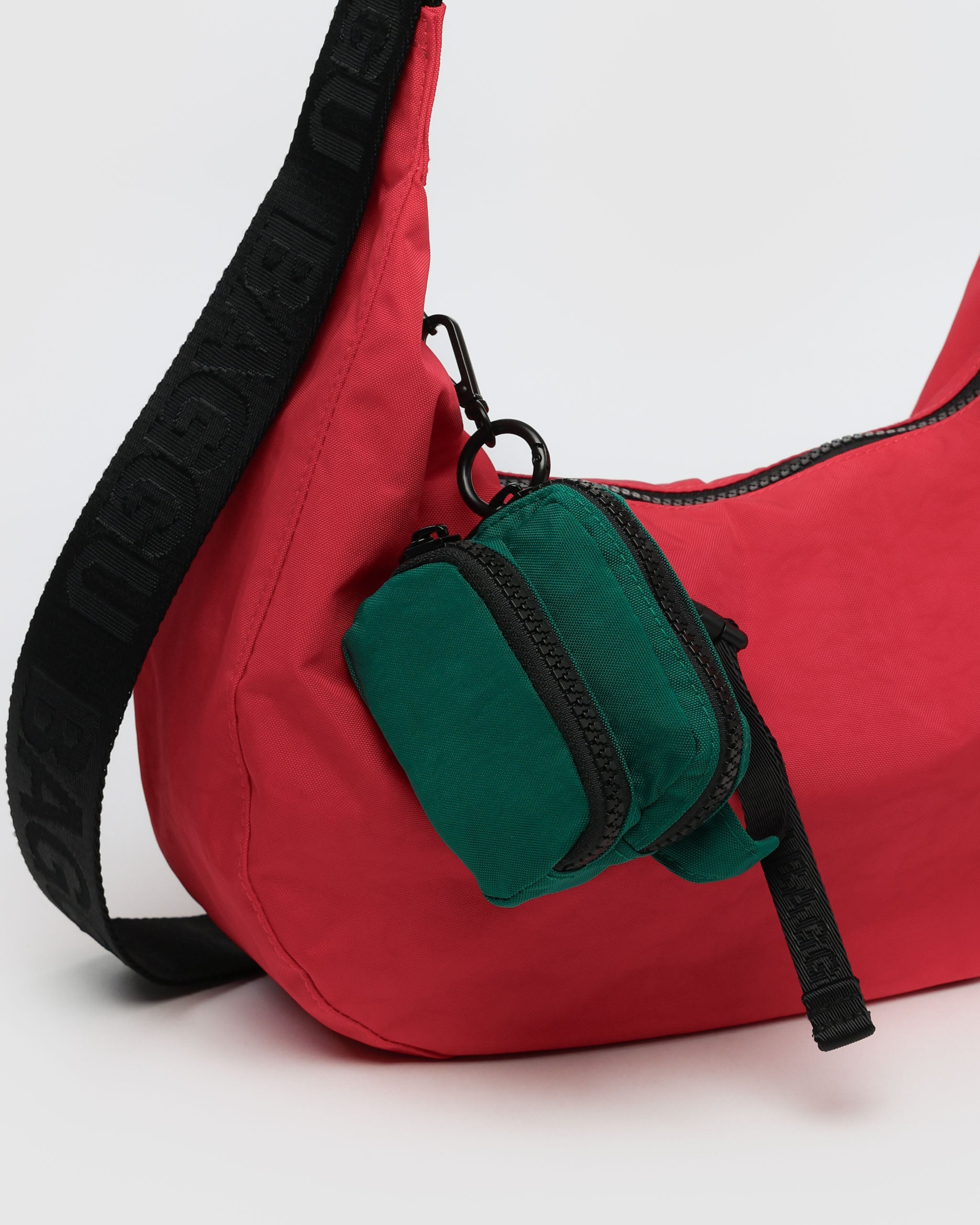 green-fanny-pack-charm-hanging-on-a-red-handbag