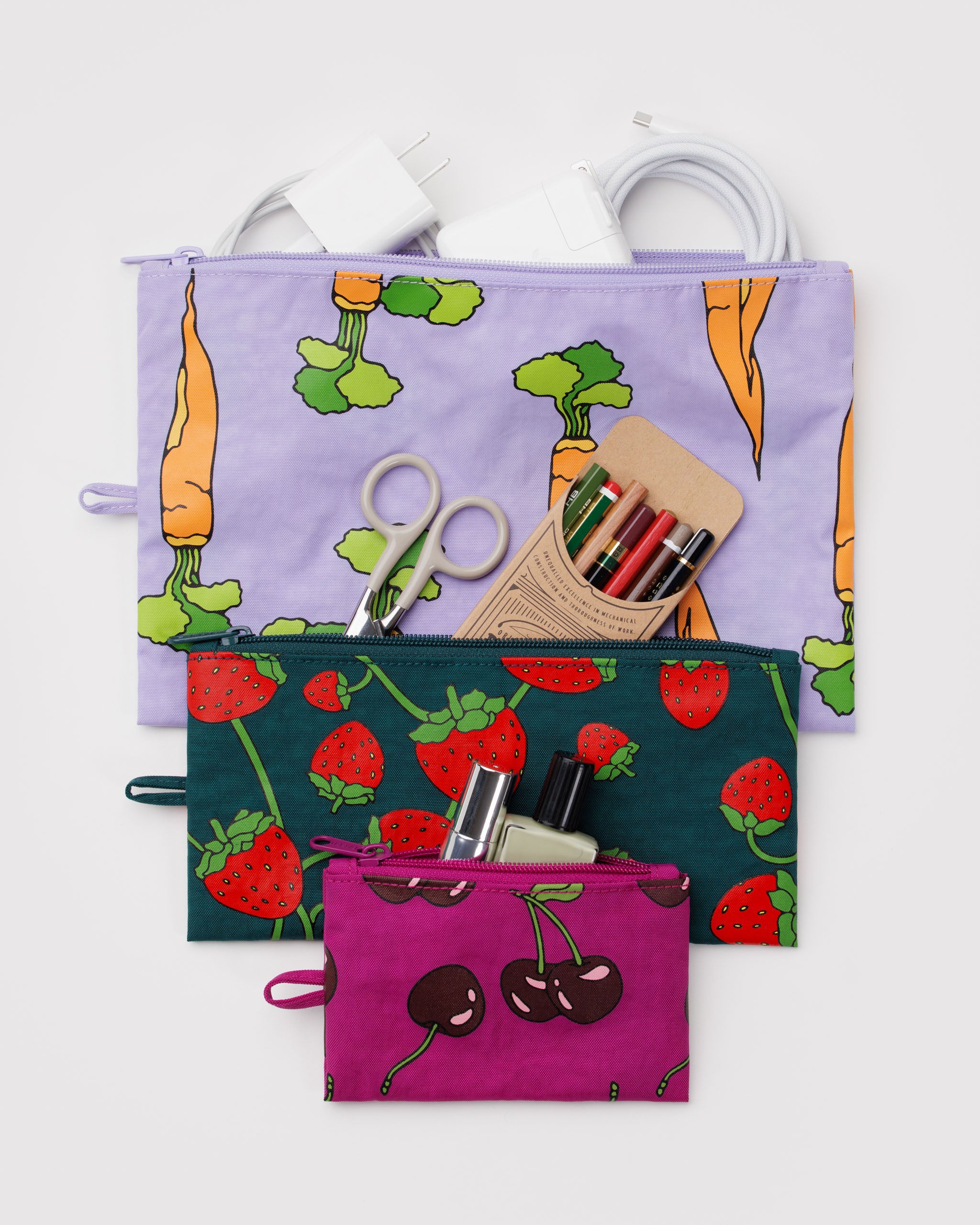 Set of three zip top pouches in different sizes with carrots, strawberry and cherry patterns, containing stationery items with a hanging loop at the side.