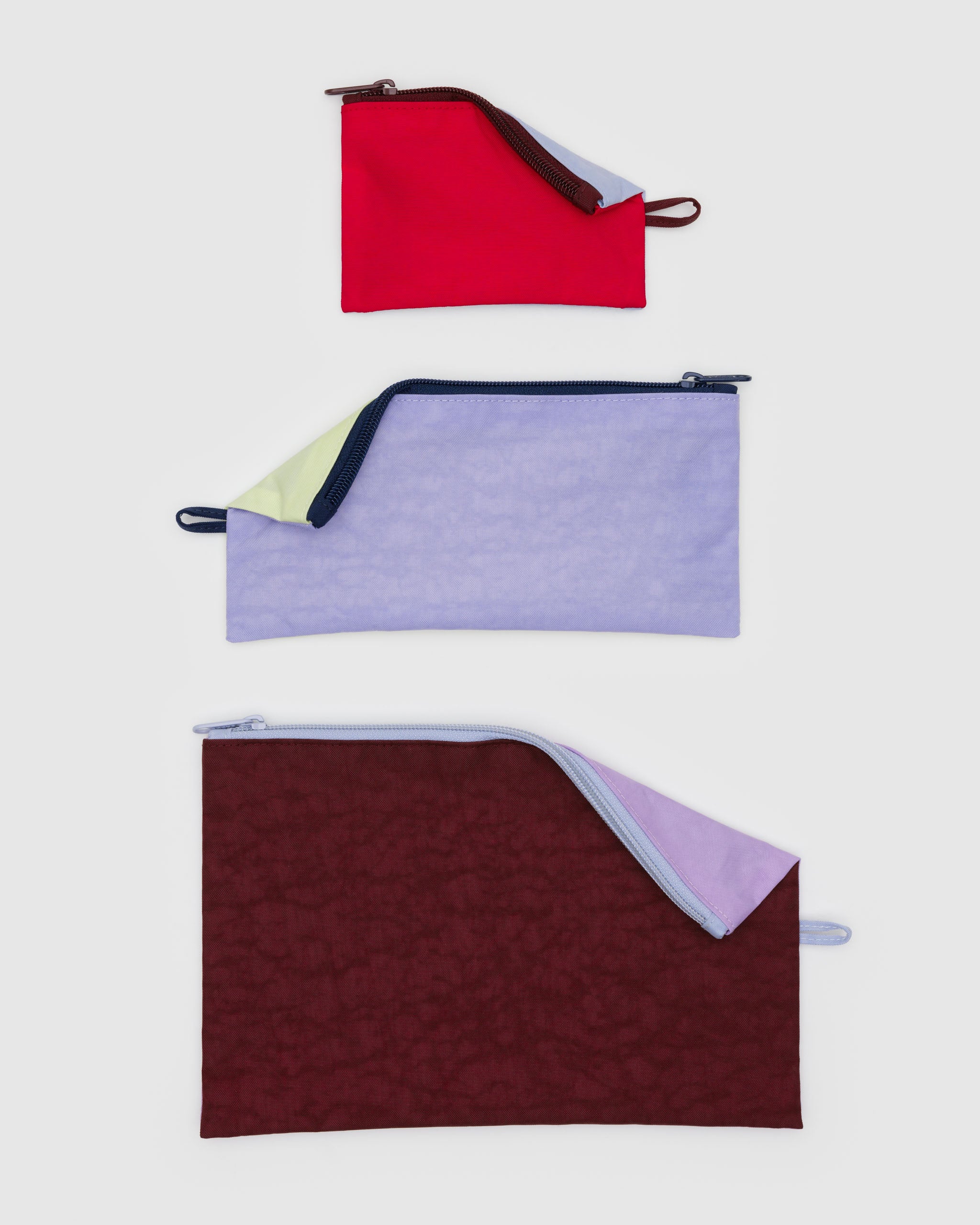 Three fabric pouches with zips and hanging loop in red, purple, and brown.