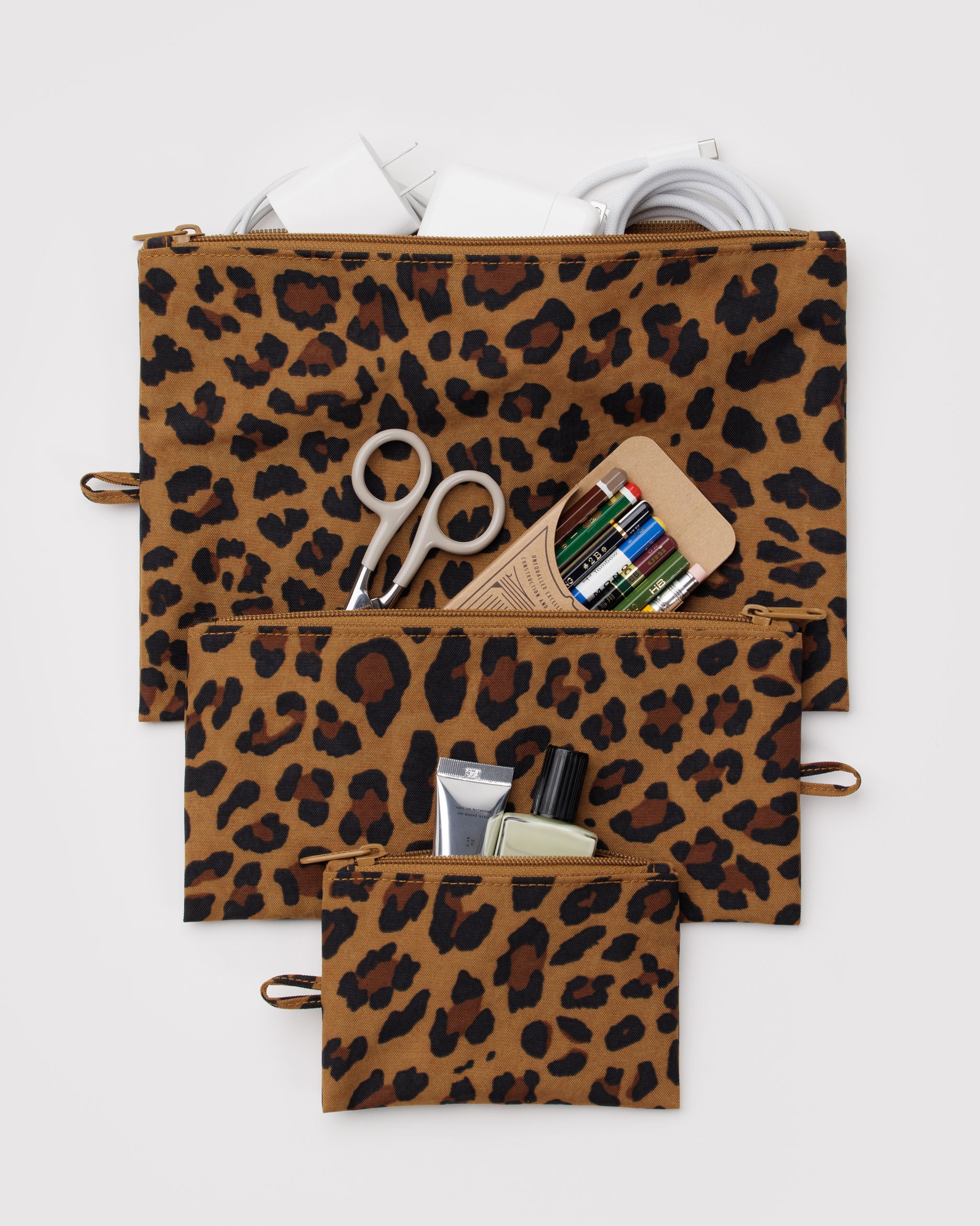 Set of three zip top pouches in different sizes with leopard print pattern, containing stationery items with a hanging loop at the side.