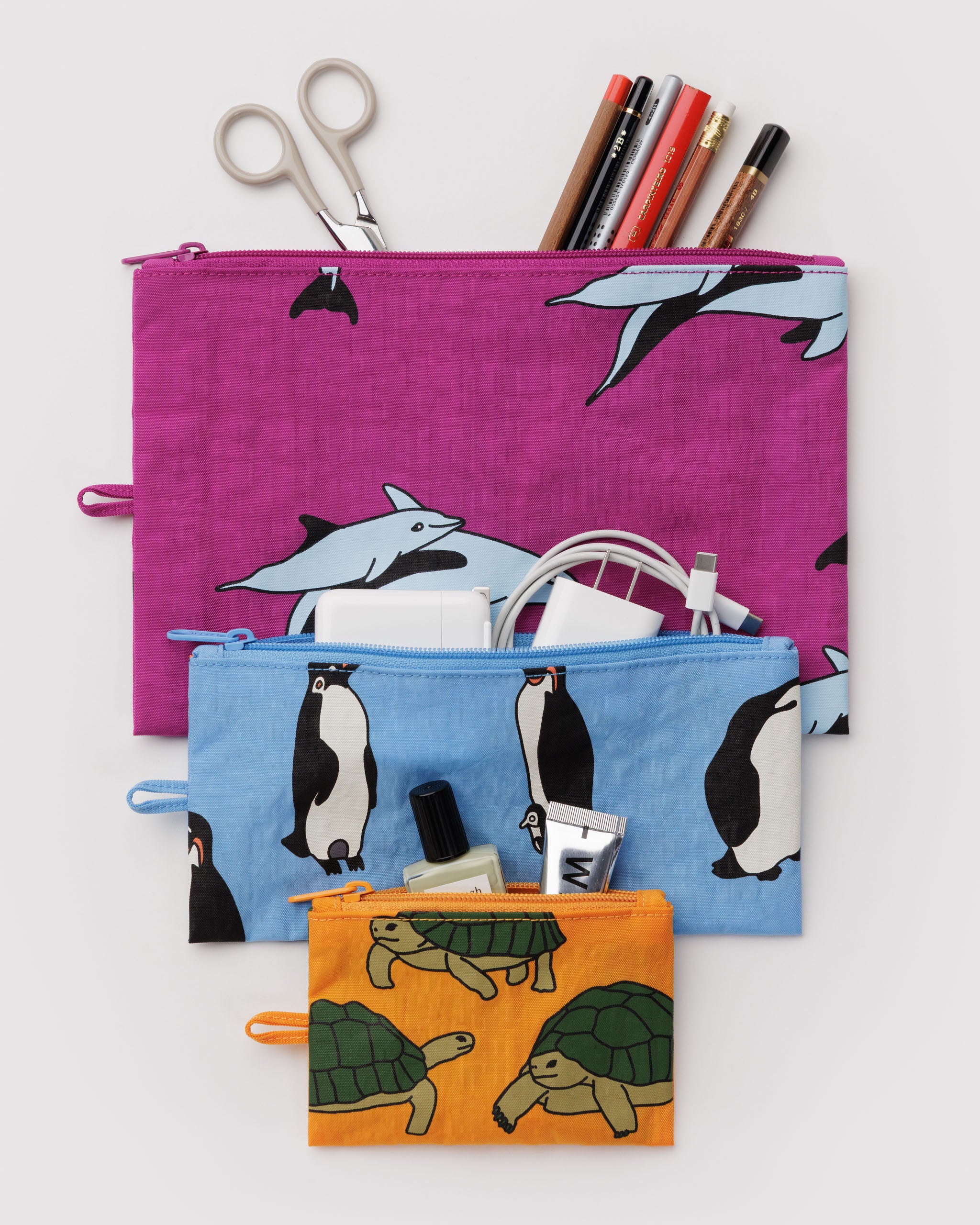 Three flat zip top pouches in an animal print with makeup, cords and stationery items organised inside.