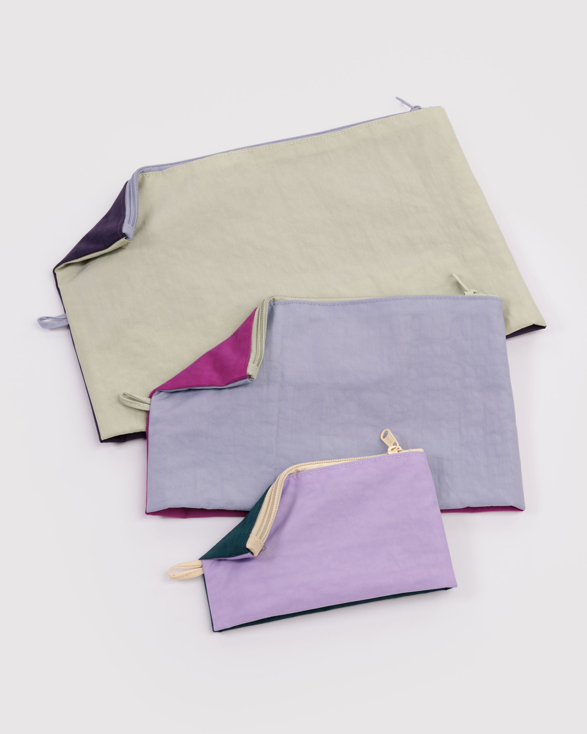 Set of three fabric pouches in different colours lying flat with edge turned over showing the colours on each side.