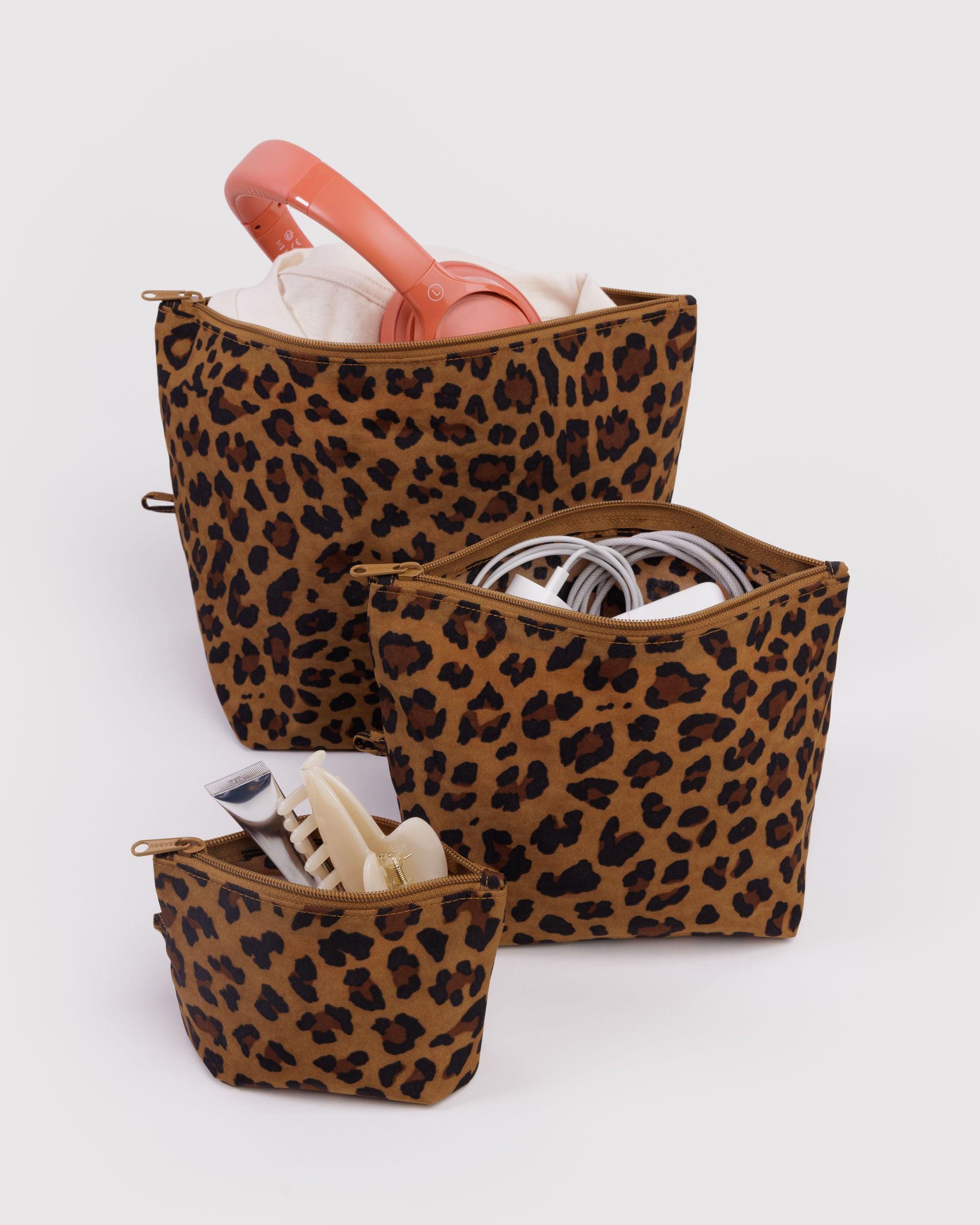 Set of leopard print zip pouches standing upright on expandable base with packed items inside bags.