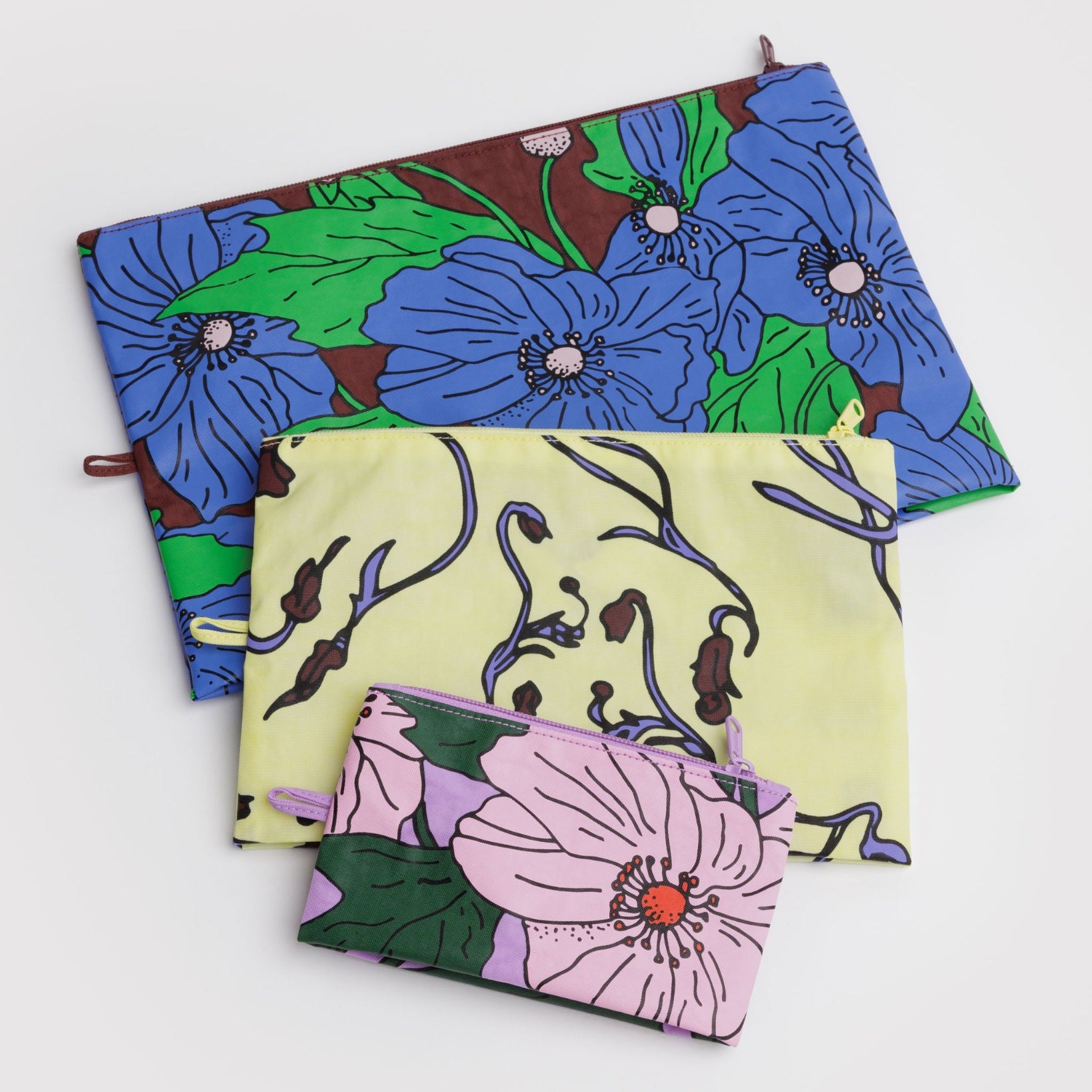 Three floral zip pouches in blue, yellow, and pink lying flat.