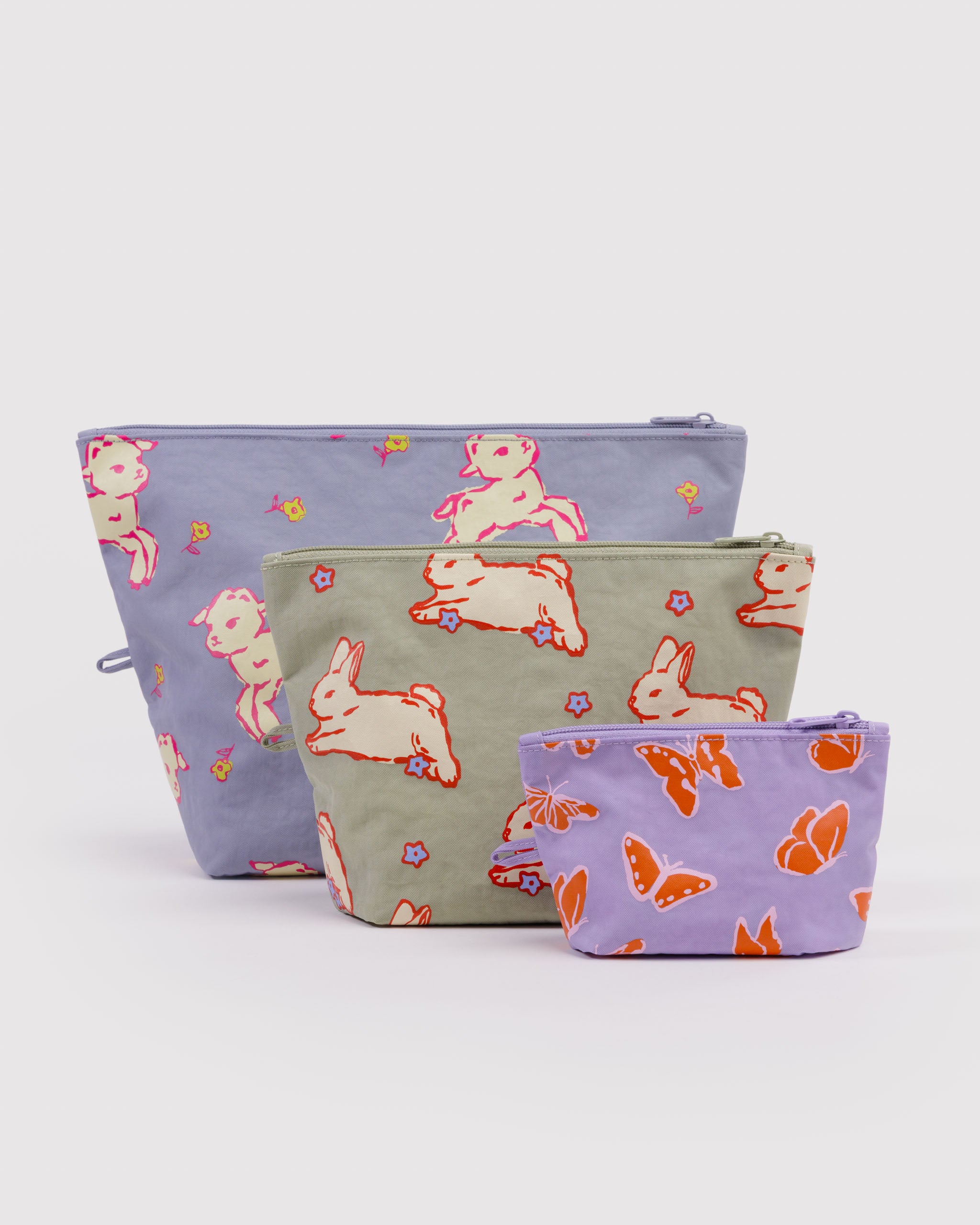 Three different sized and pastel coloured, expanded zip top pouches and spring animal patterns on each with items inside, hanging loop and standing upright on flat bottom.