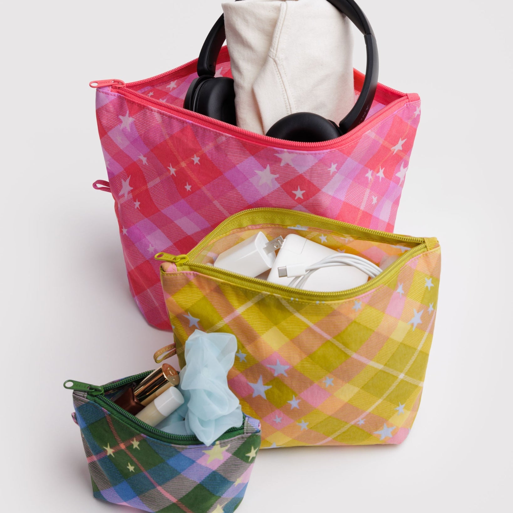 Set of 3 colourful plaid bags with zip open and items inside.