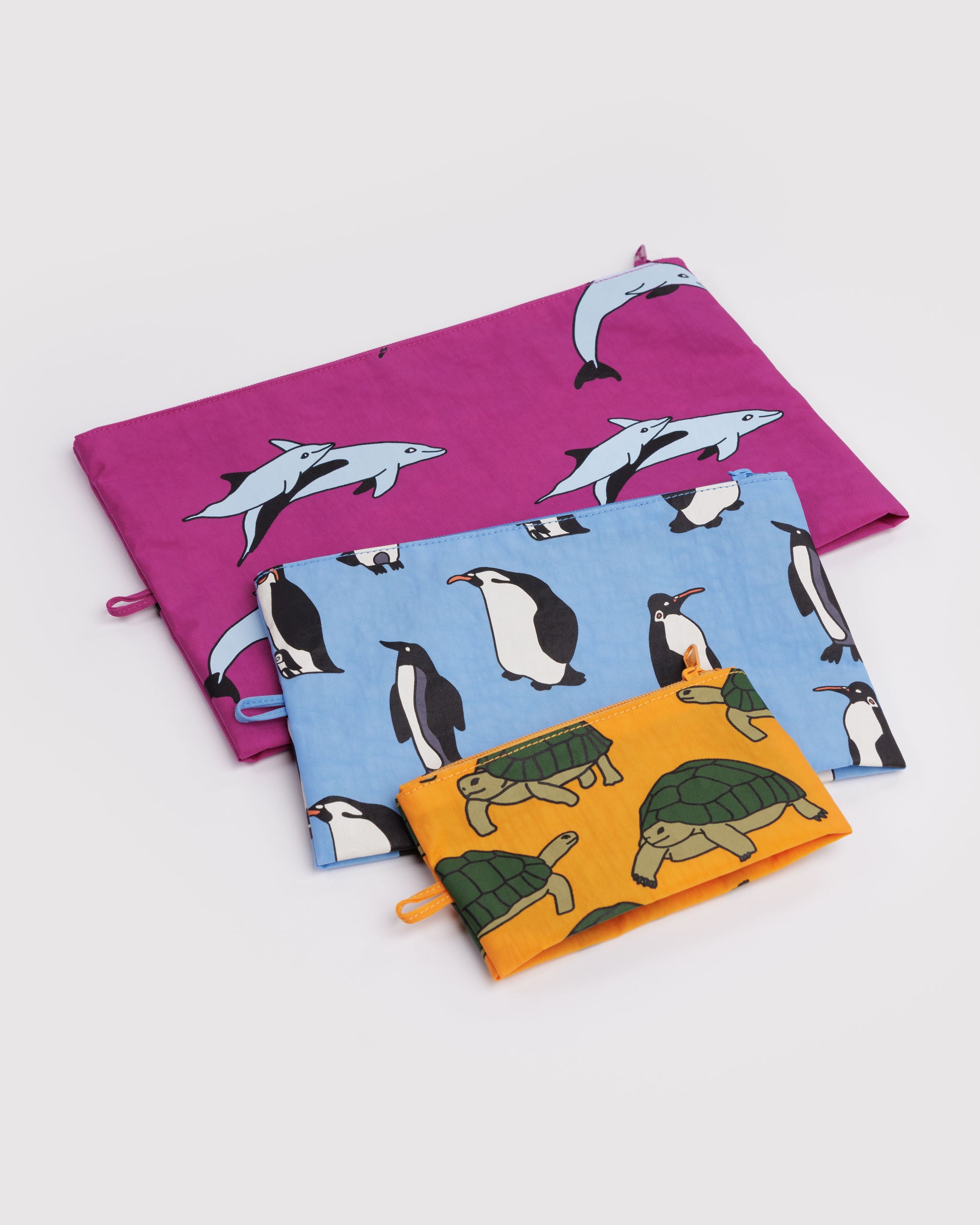Three empty zip top pouches in a pink, blue and orange with animal patterns and hanging loop lying flat.