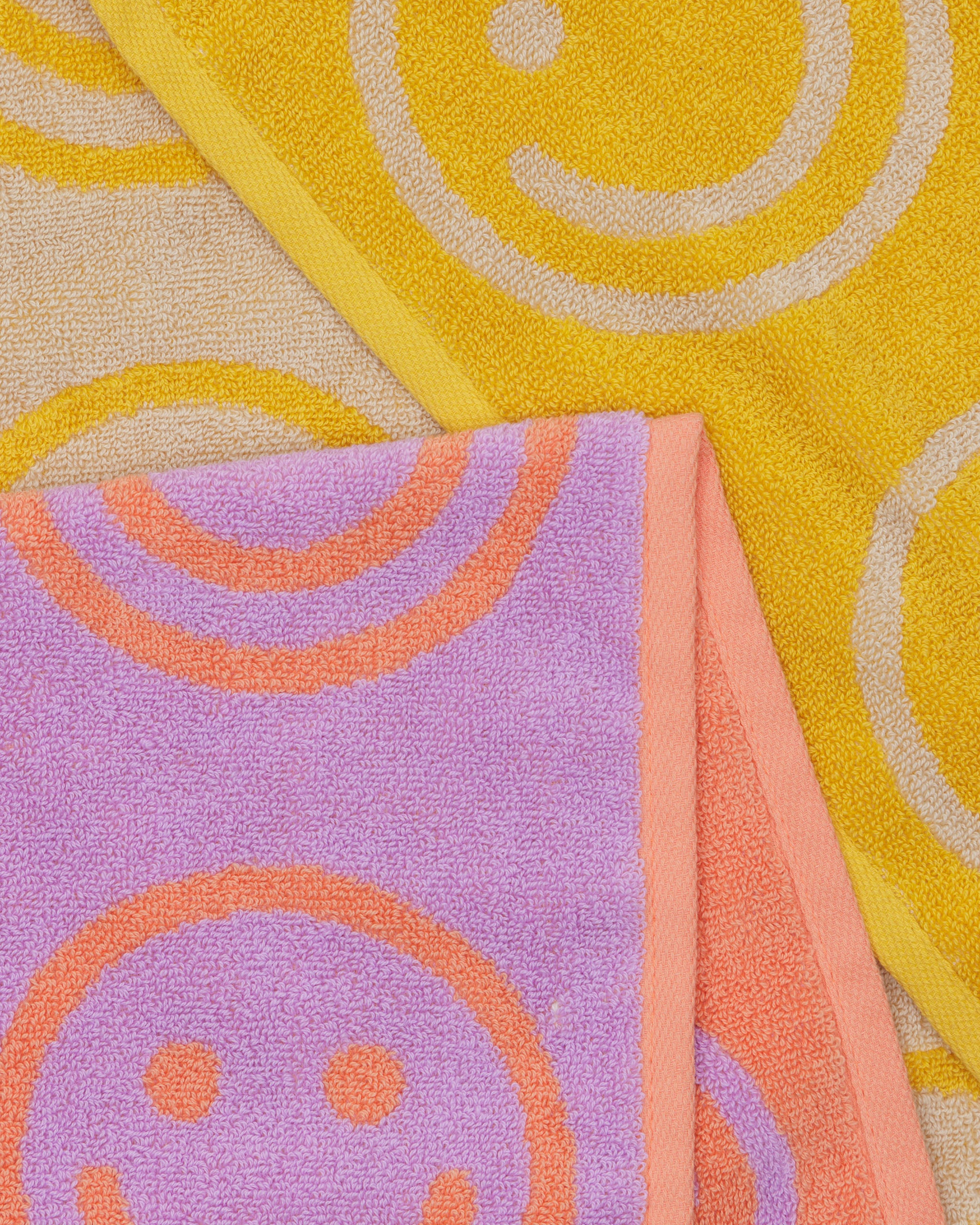 smiley-face-pattern-on-towels-with-contrast-colour-at-edge-in-colours-lilac-orange-and-marigold-cream