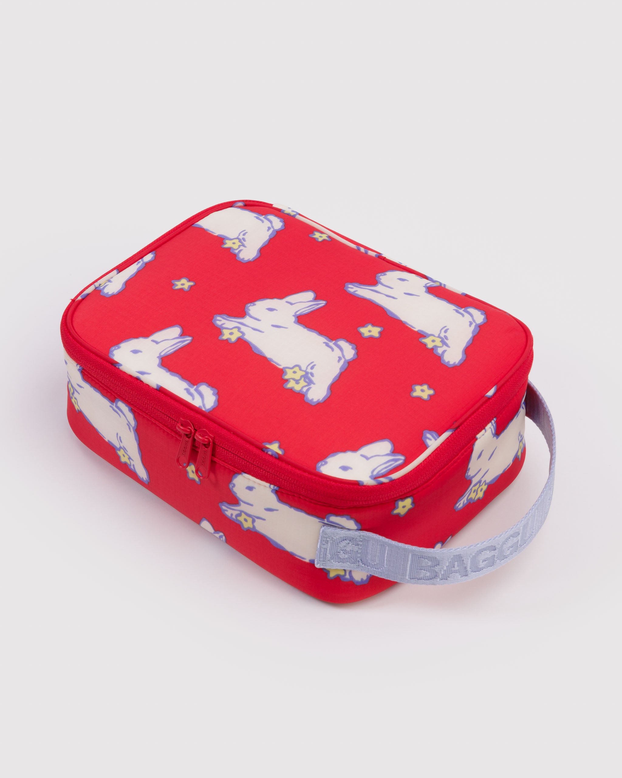 Red lunch box with bunny pattern, zip closure and light blue webbed handle.
