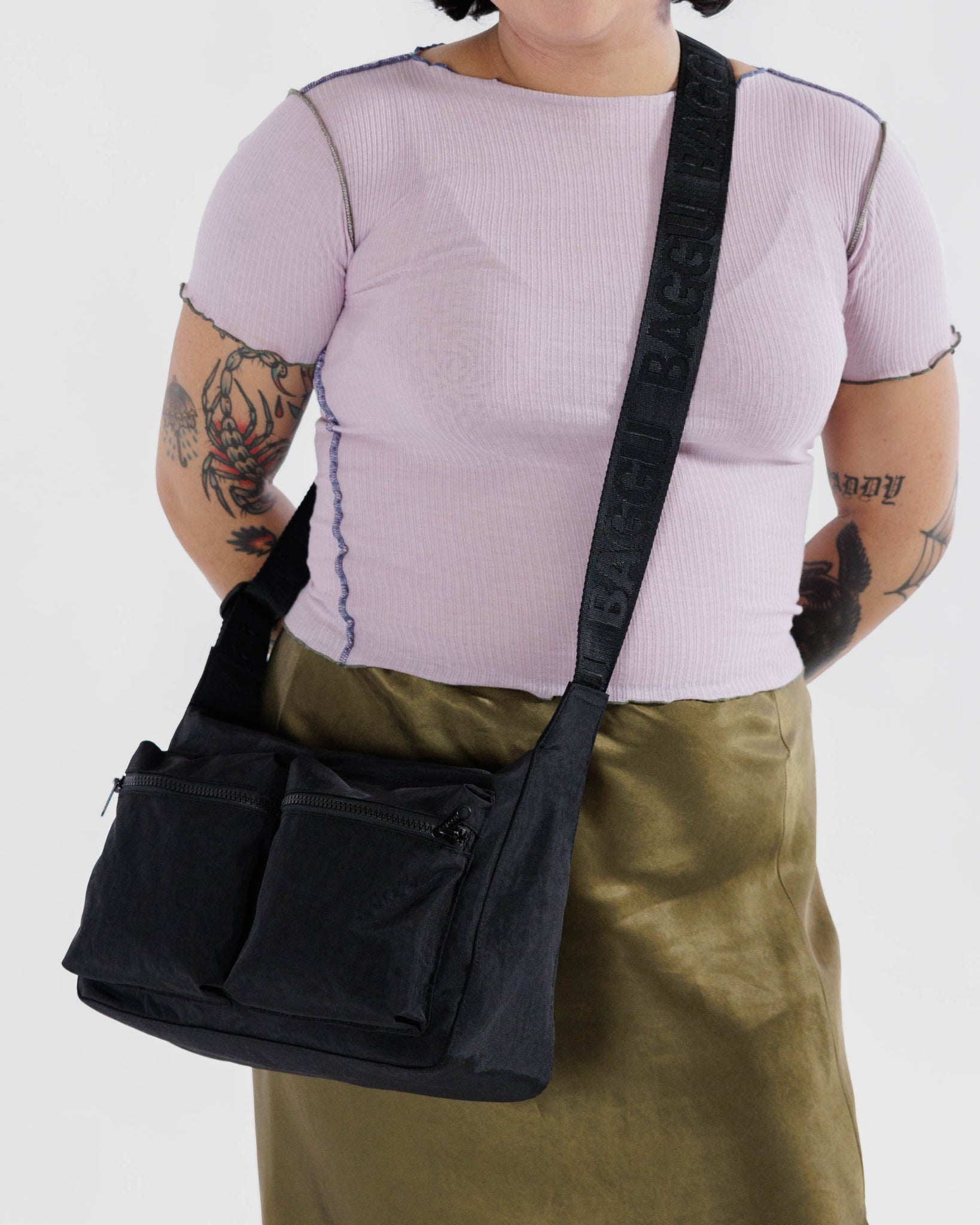 Person wearing a black cargo crossbody with front zip pockets.