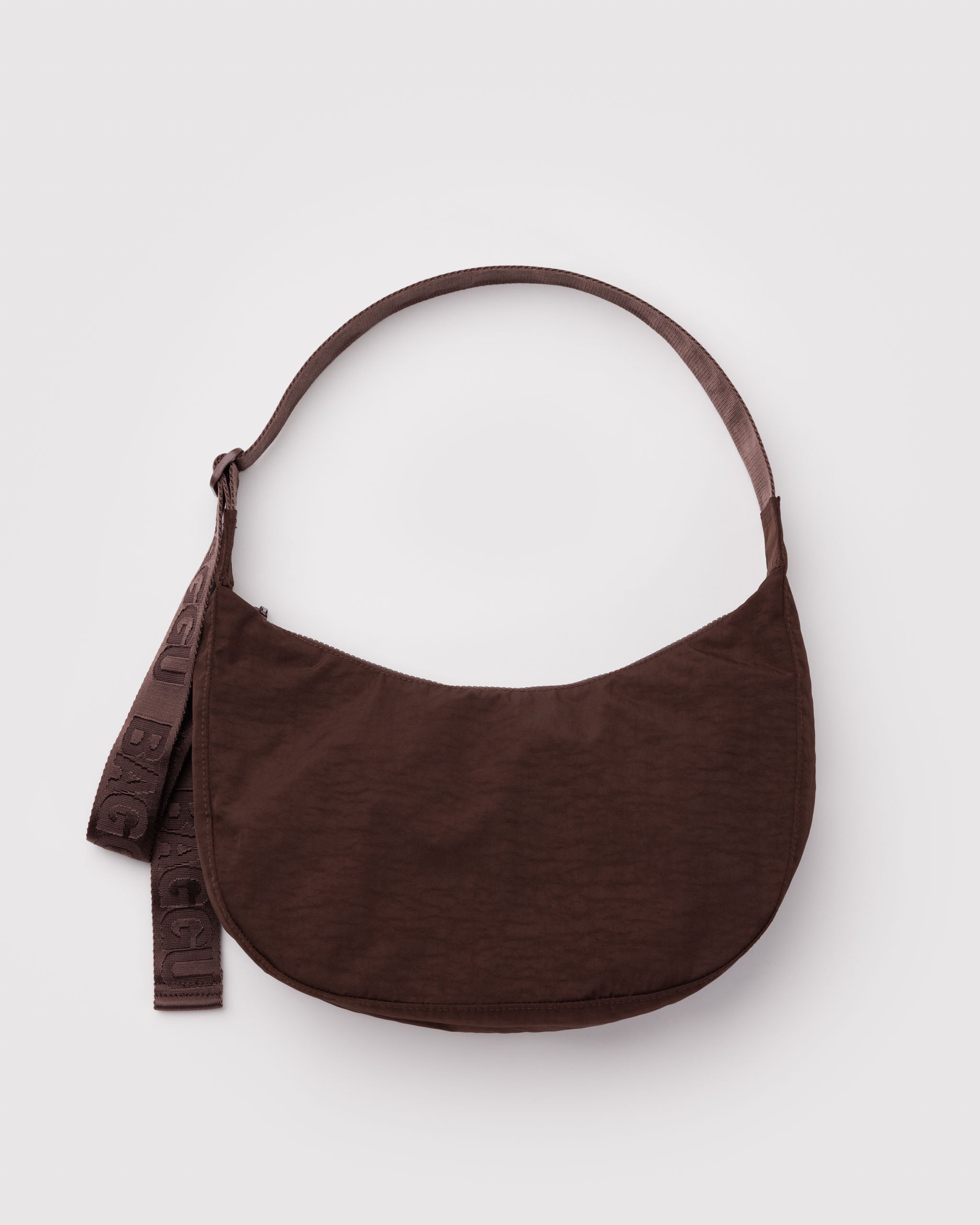 Brown crossbody bag in a crescent shape with a wide webbed adjustable strap and top zip.