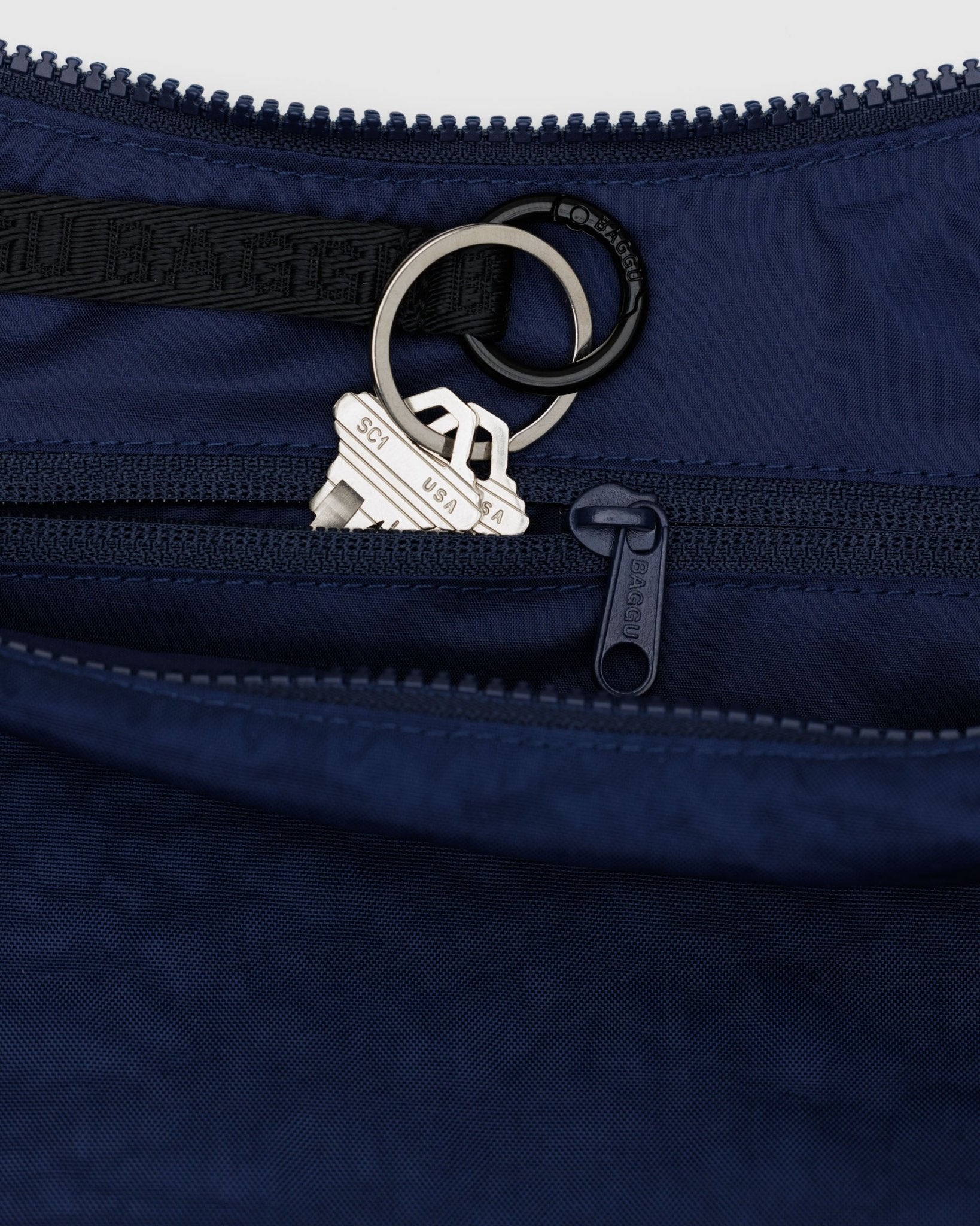 Inside zip of a Baggu Medium Nylon Crescent Bag in Navy showing internal zip pouch and key leash