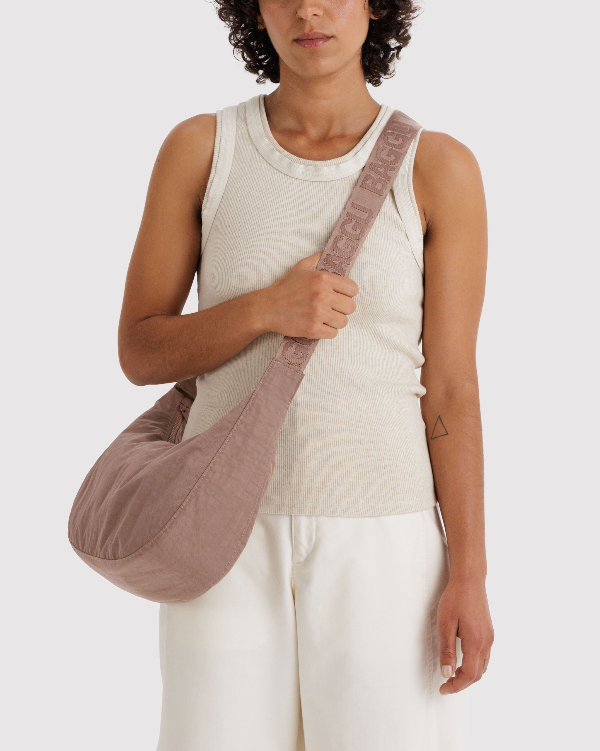 Woman carrying a brown bag crossbody on shoulder.