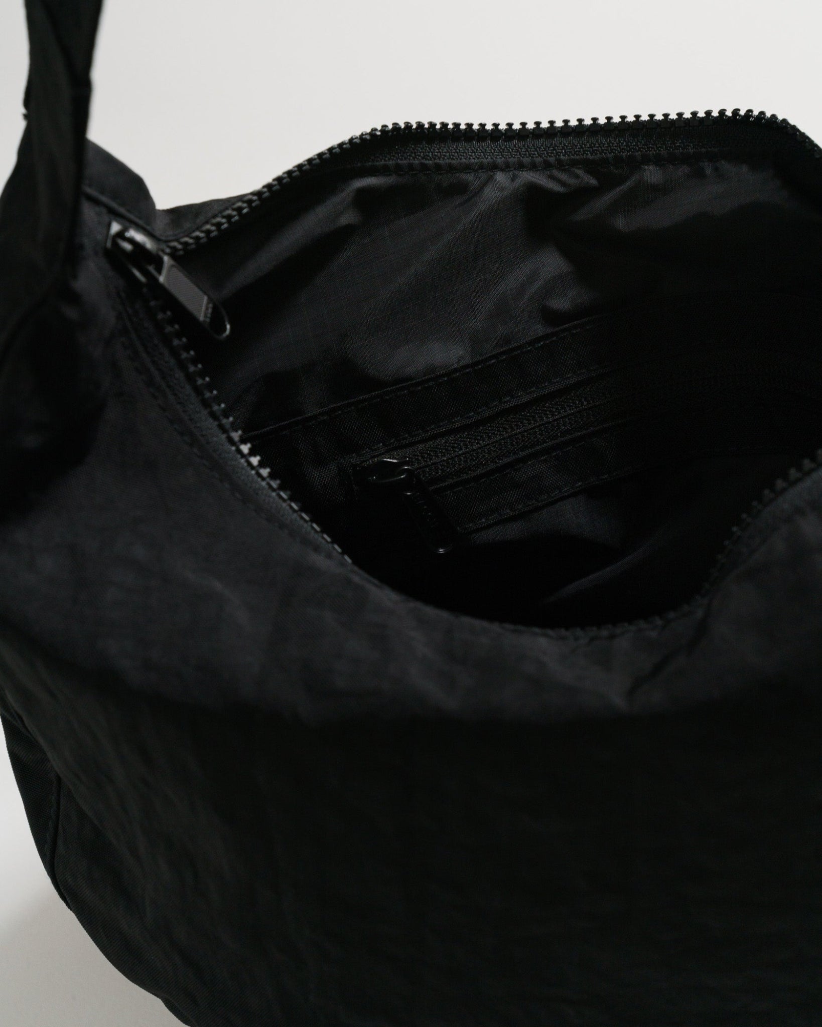 Close-up of a black bag with top zipper open.