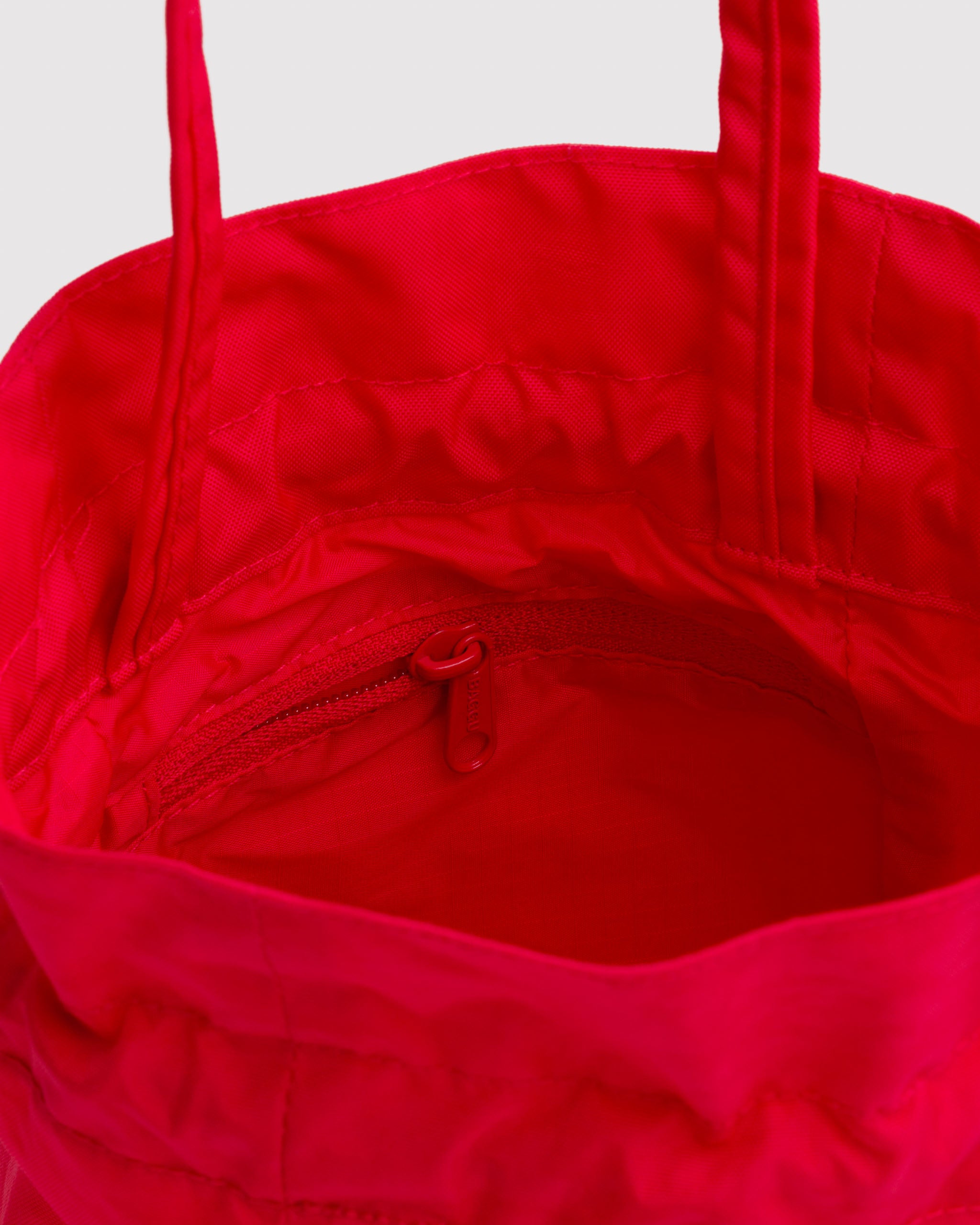 Close-up of a red drawstring bag with an interior zipper pocket and red lining.
