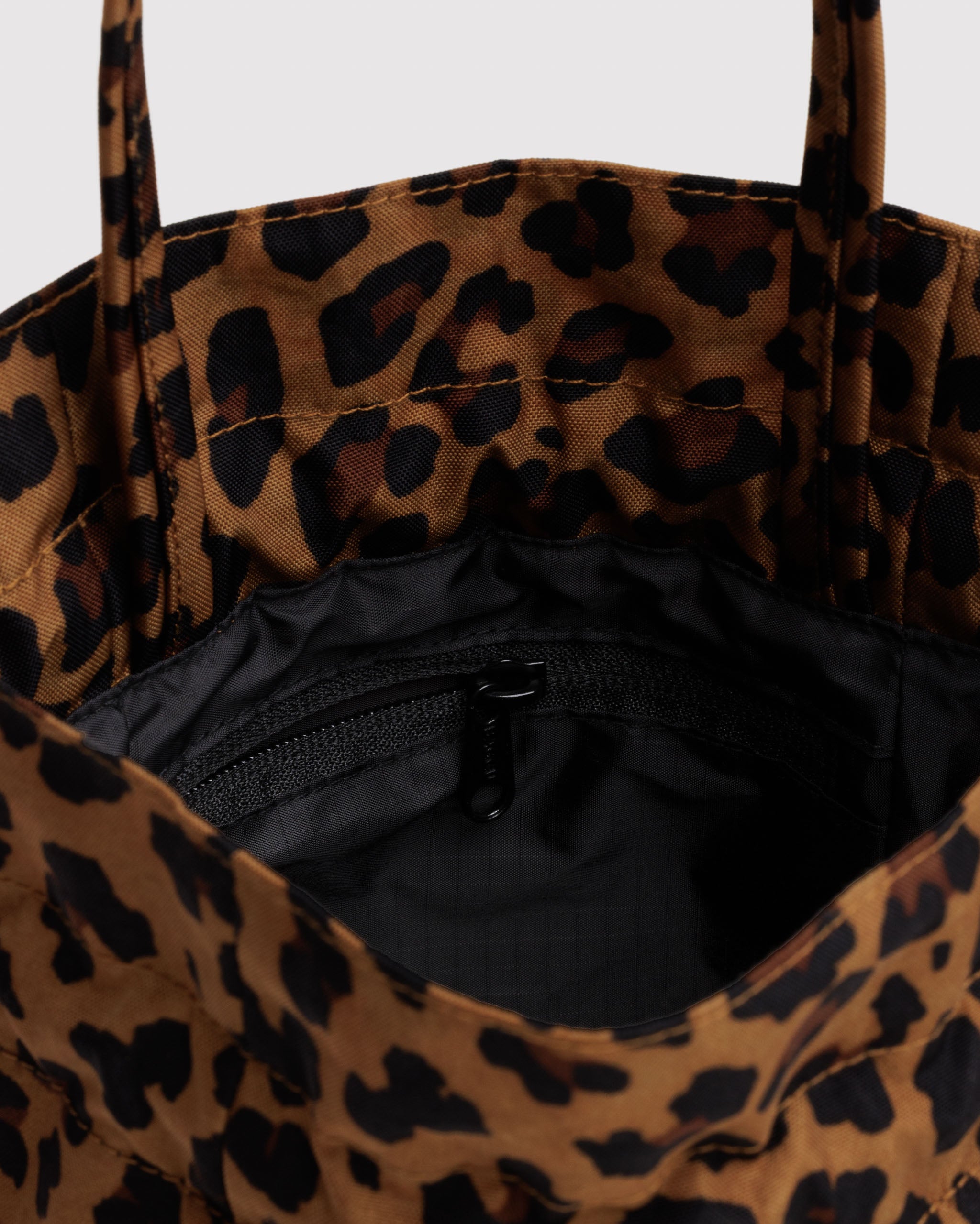 Leopard print drawstring top tote bag with black interior and zip pouch.