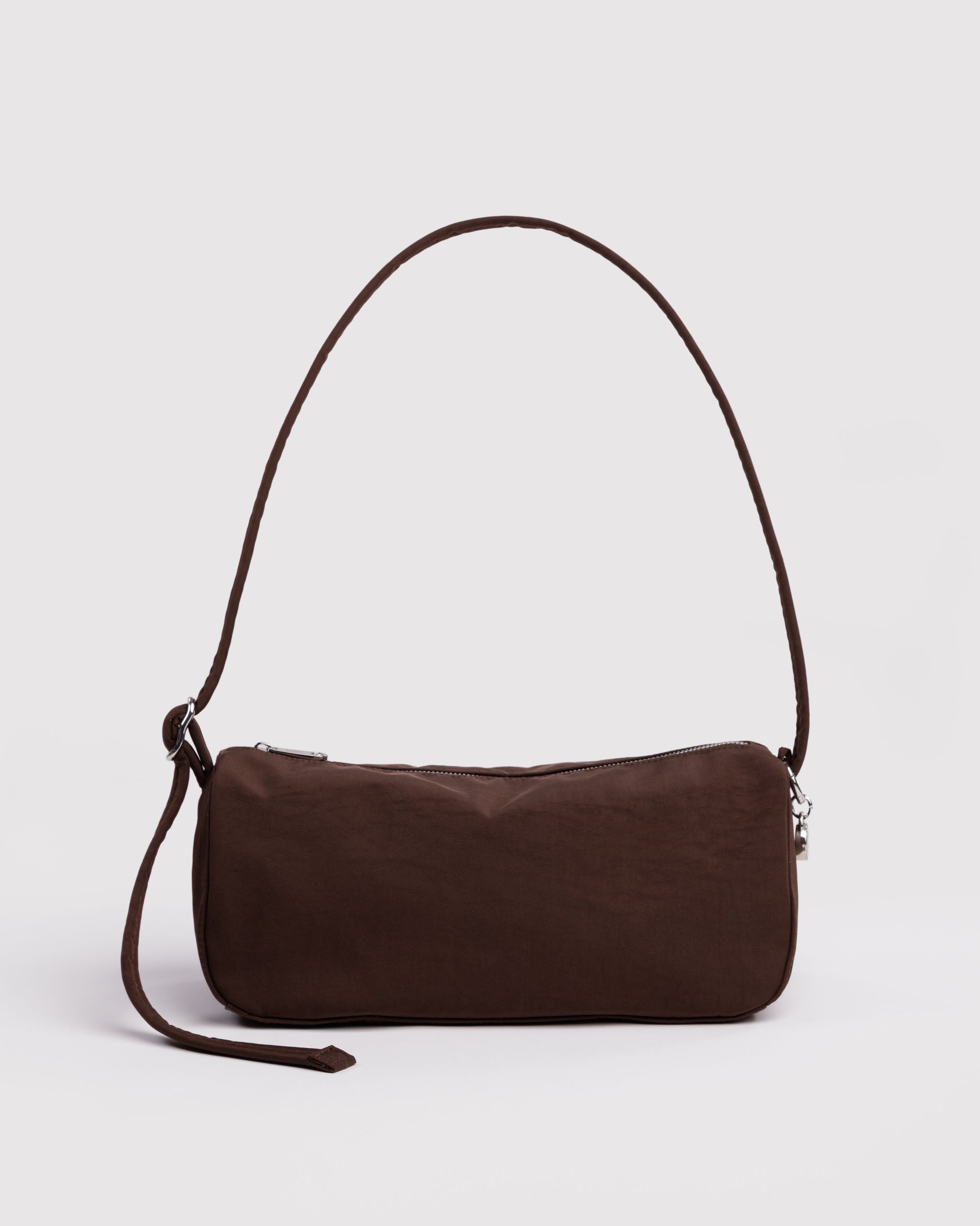 Brown shoulder handbag with an adjustable strap and zip closure with smiley face charm attached to strap.