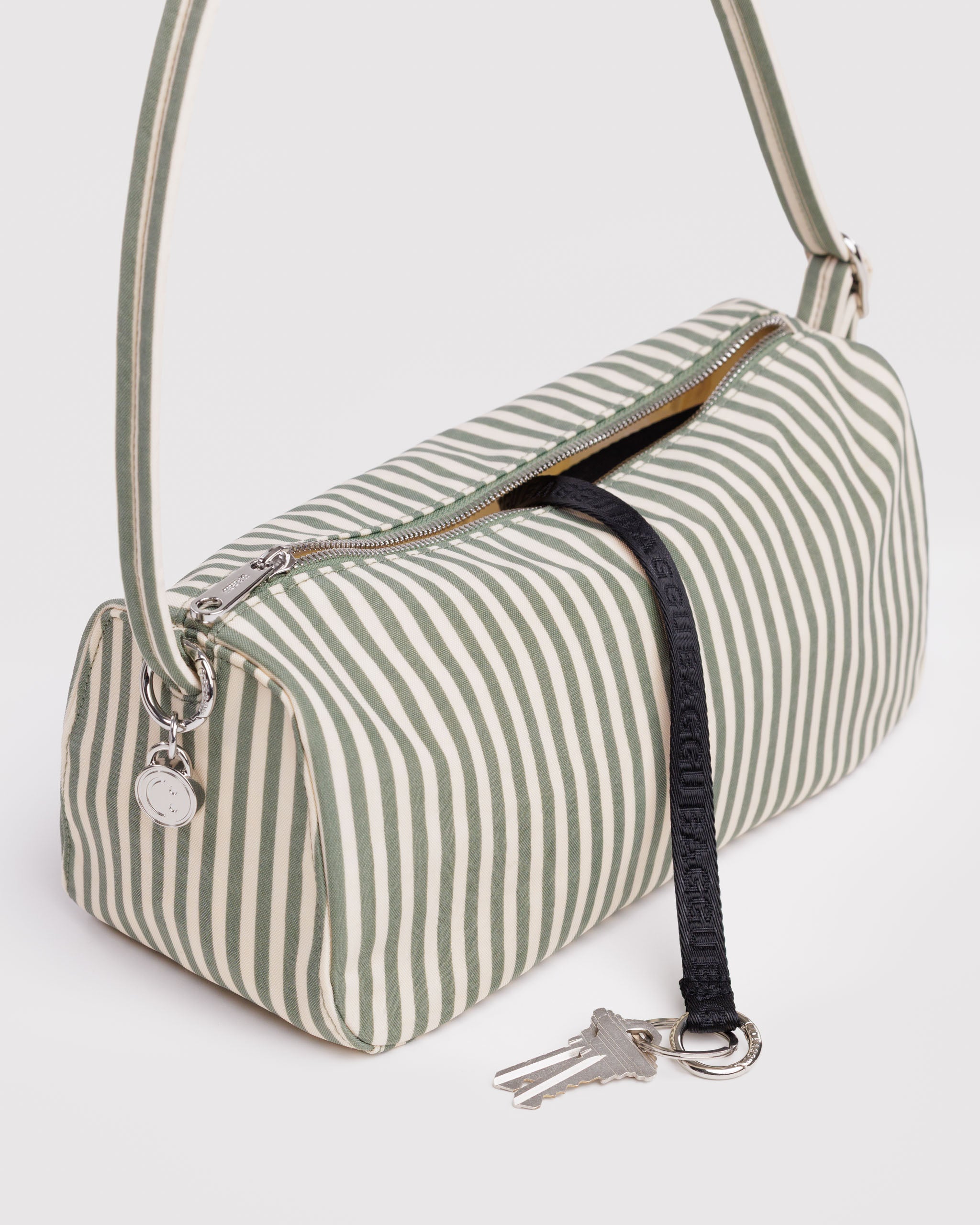 Green and cream striped handbag with a keychain attached inside and metal smiley face charm.
