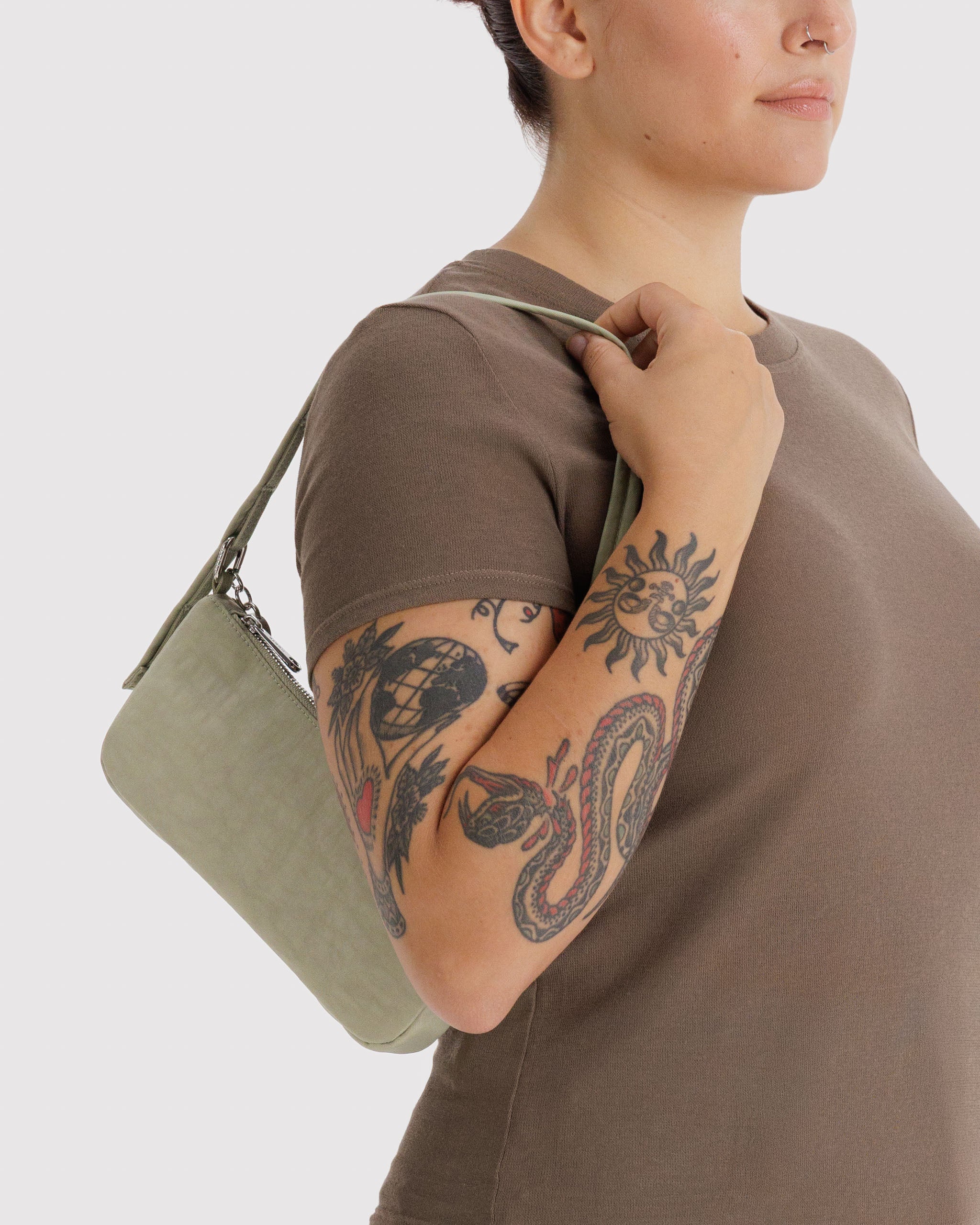 Person wearing a brown shirt holding a light green bag on shoulder.