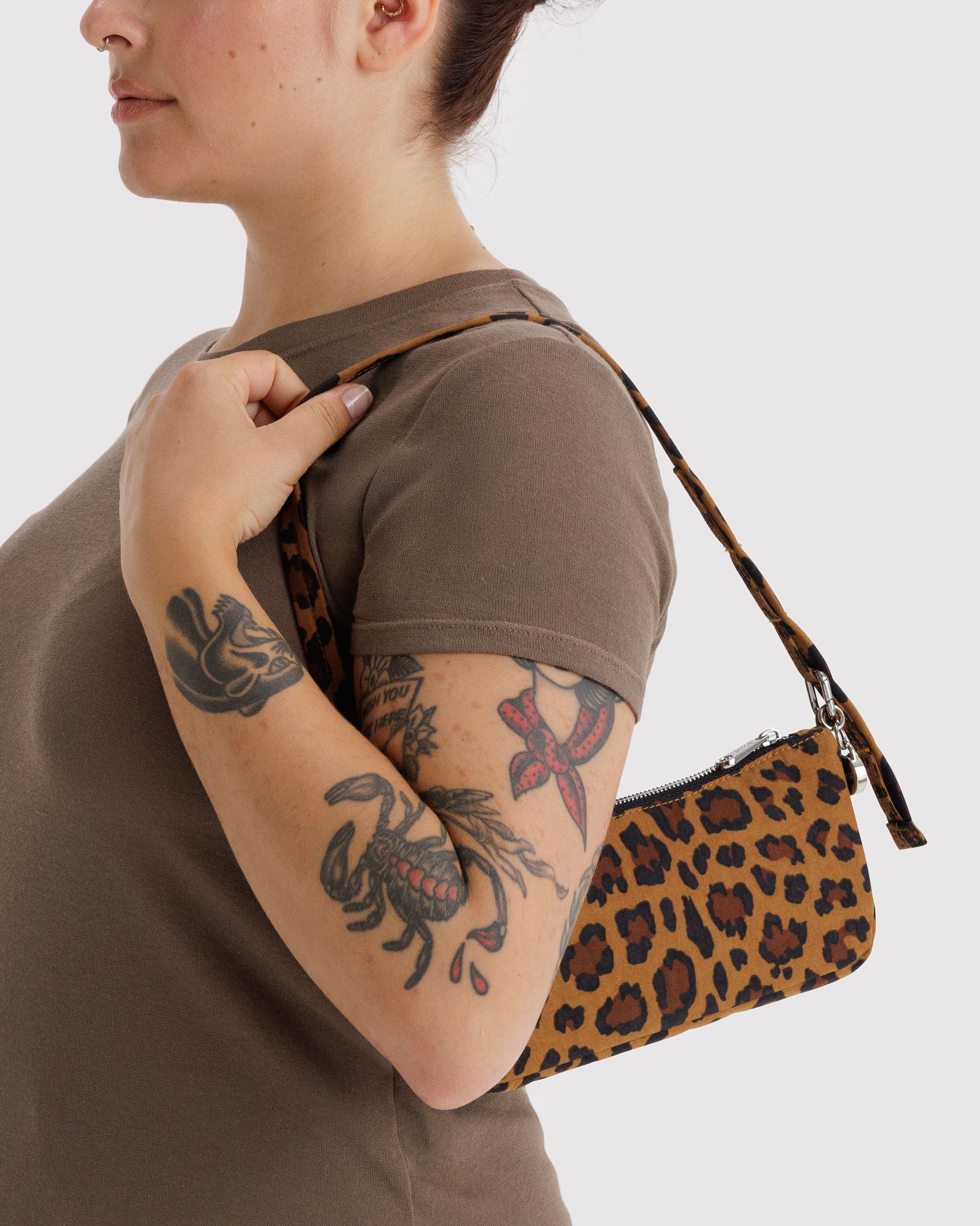 Person wearing a brown shirt with a leopard print handbag over their shoulder.