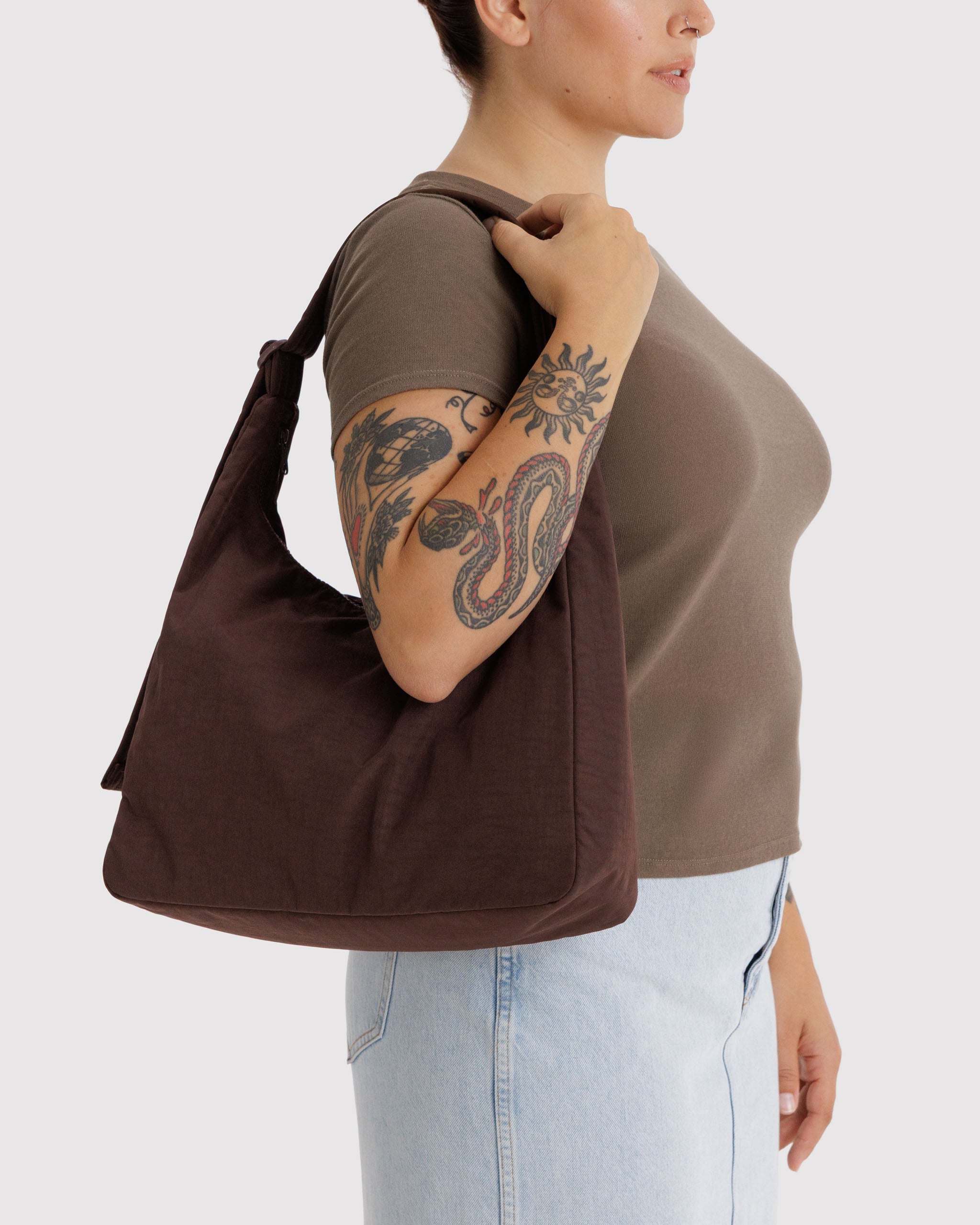 Person wearing a brown handbag on shoulder with an adjustable shoulder strap.