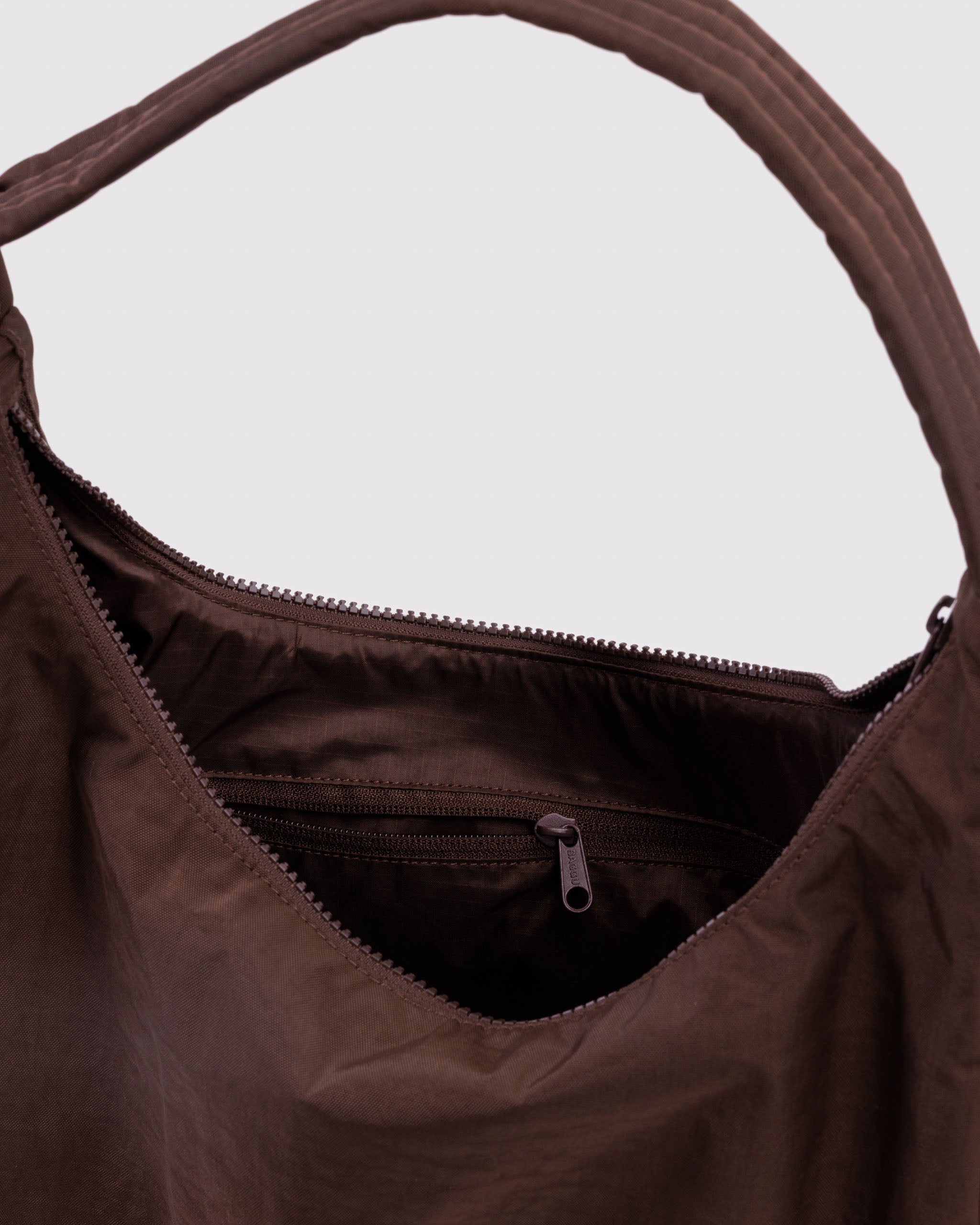Brown handbag with a visible top zipper ad internal zip pocket.