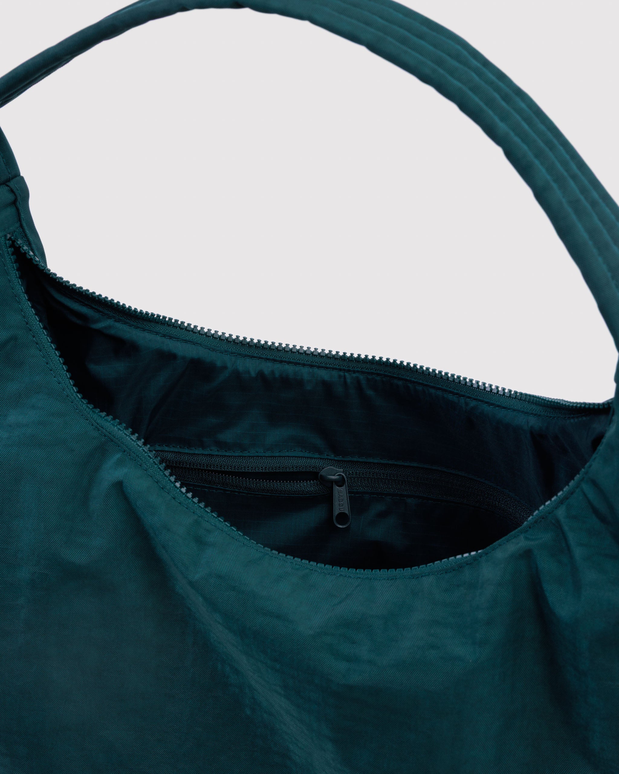 Teal green shoulder bag with a zipper and a quilted and adjustable shoulder strap with an internal zip pocket.