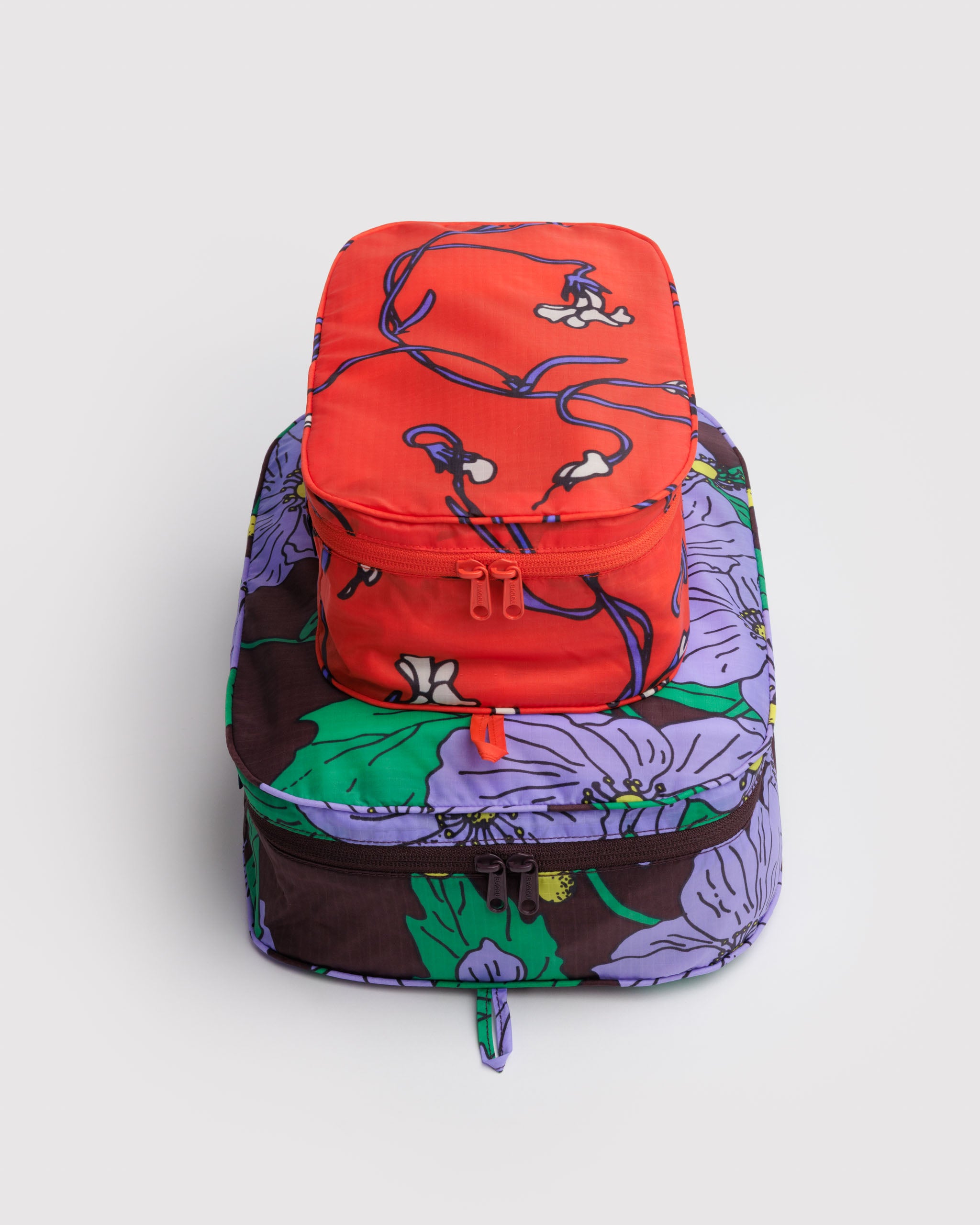 Stack of two floral-patterned packing cubes with zips and hanging loop.
