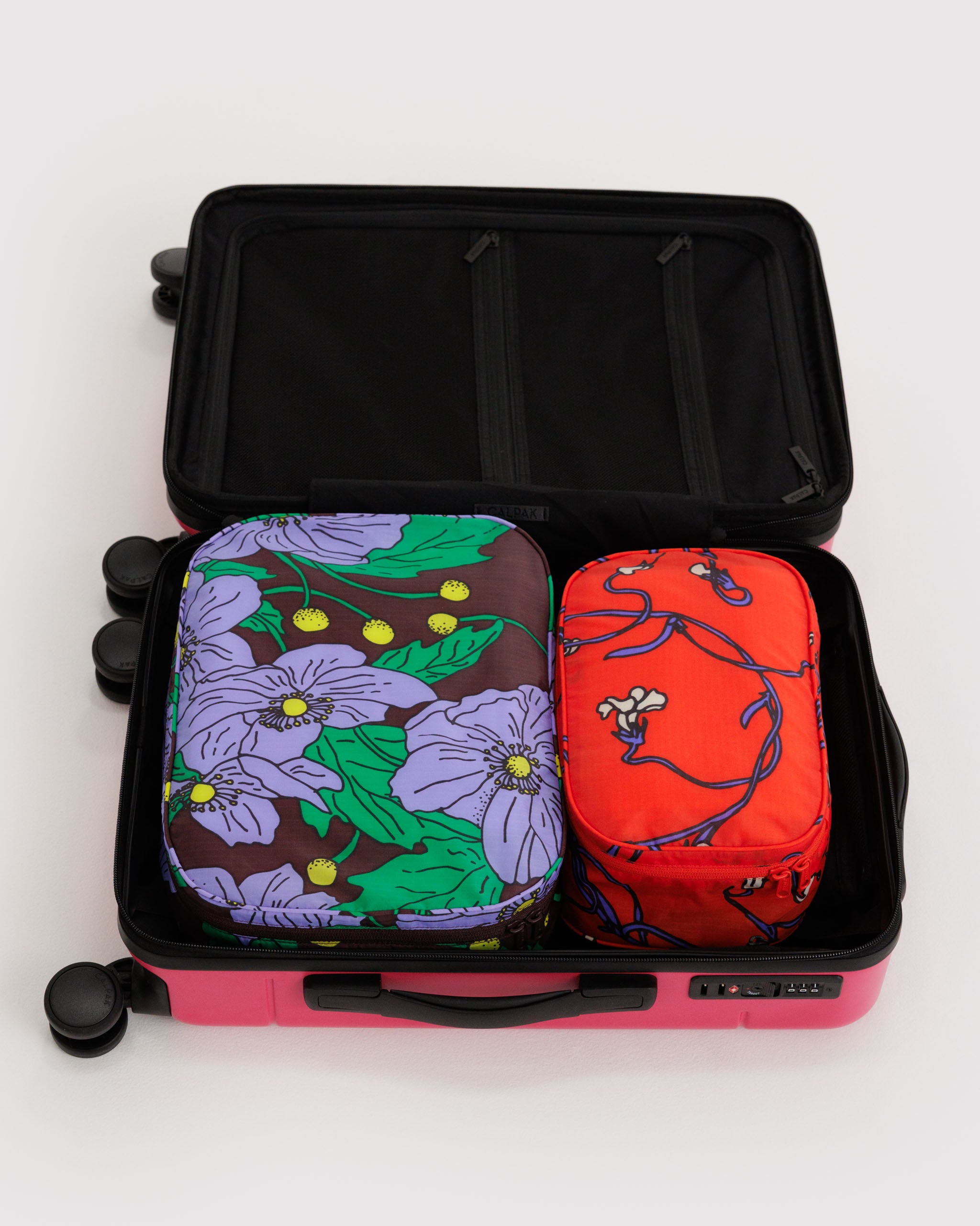 Two different sized zip packing cubes with floral poppy designs inside an open suitcase.