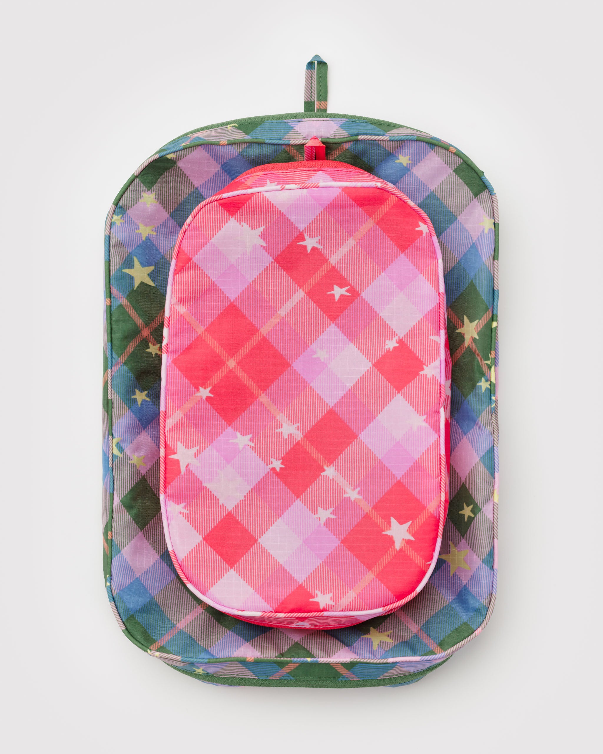Stack of two, medium and small, colourful plaid packing cube bags with stars in pink and a green.