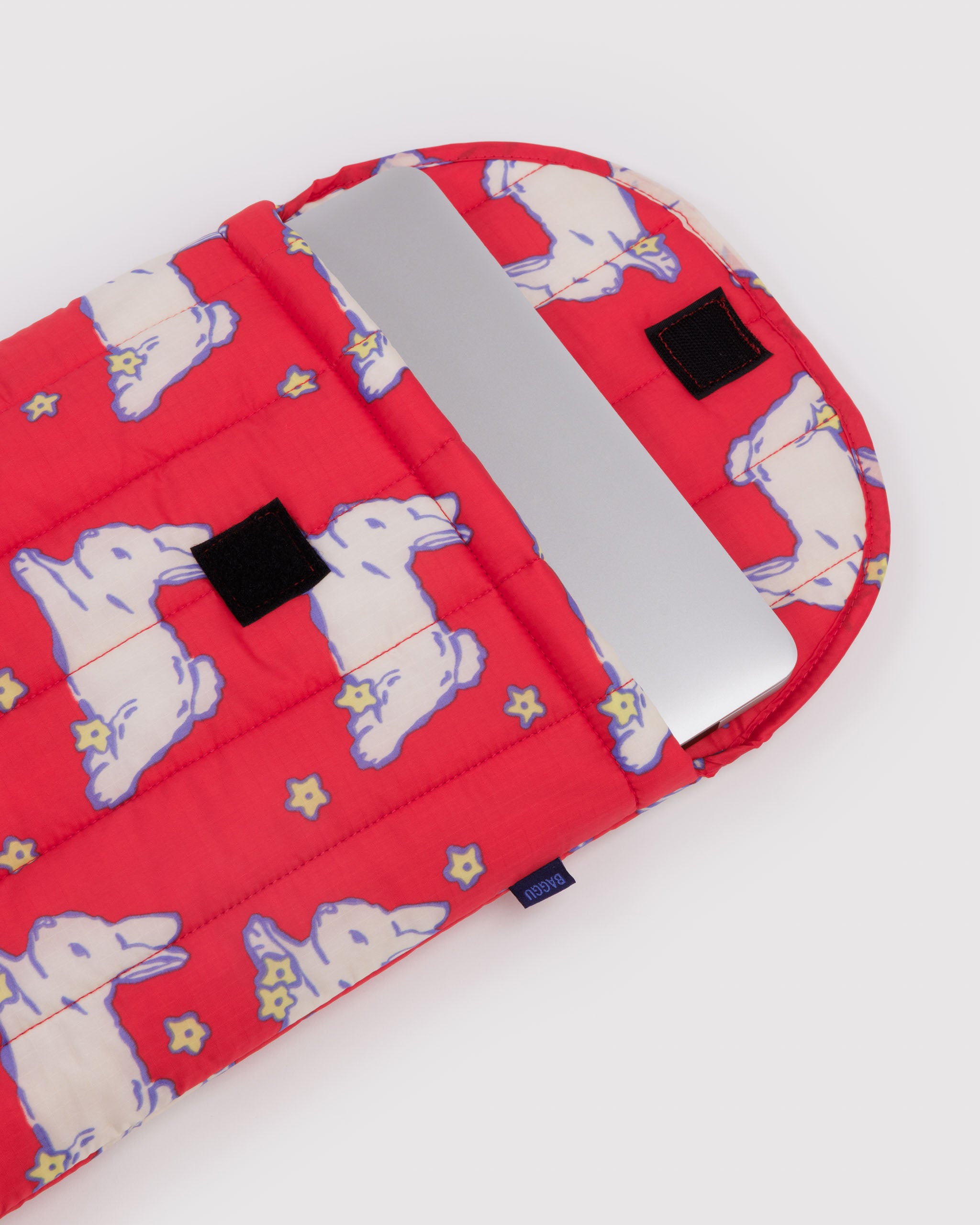 Red quilted and puffy sleeve with white bunnies pattern and a silver laptop inside with velcro closure.