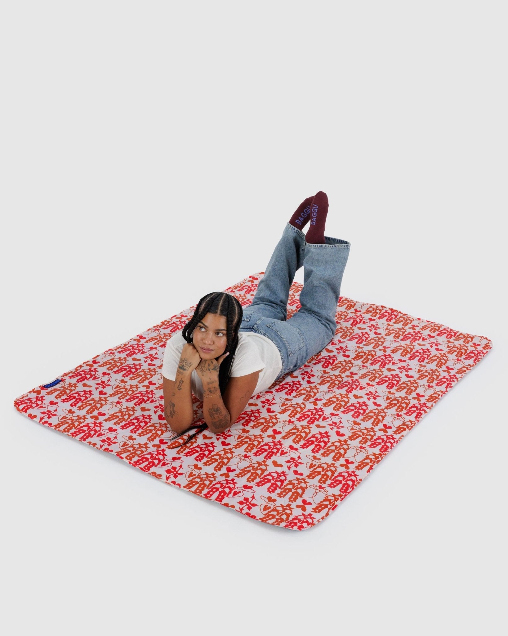 Woman lying on a Baggu Puffy Picnic Blanket with Cowgirl pattern