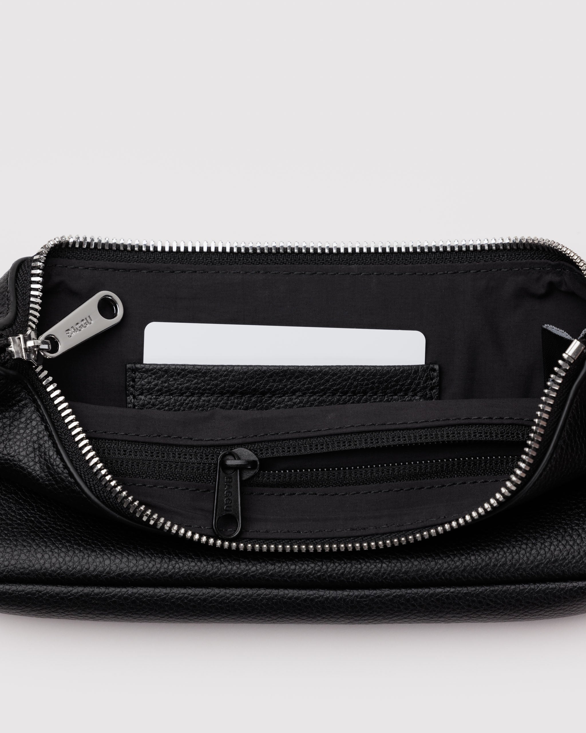Black leather bag with a metal zipper open showing inside black lining with a zip pocket and black leather card slots.