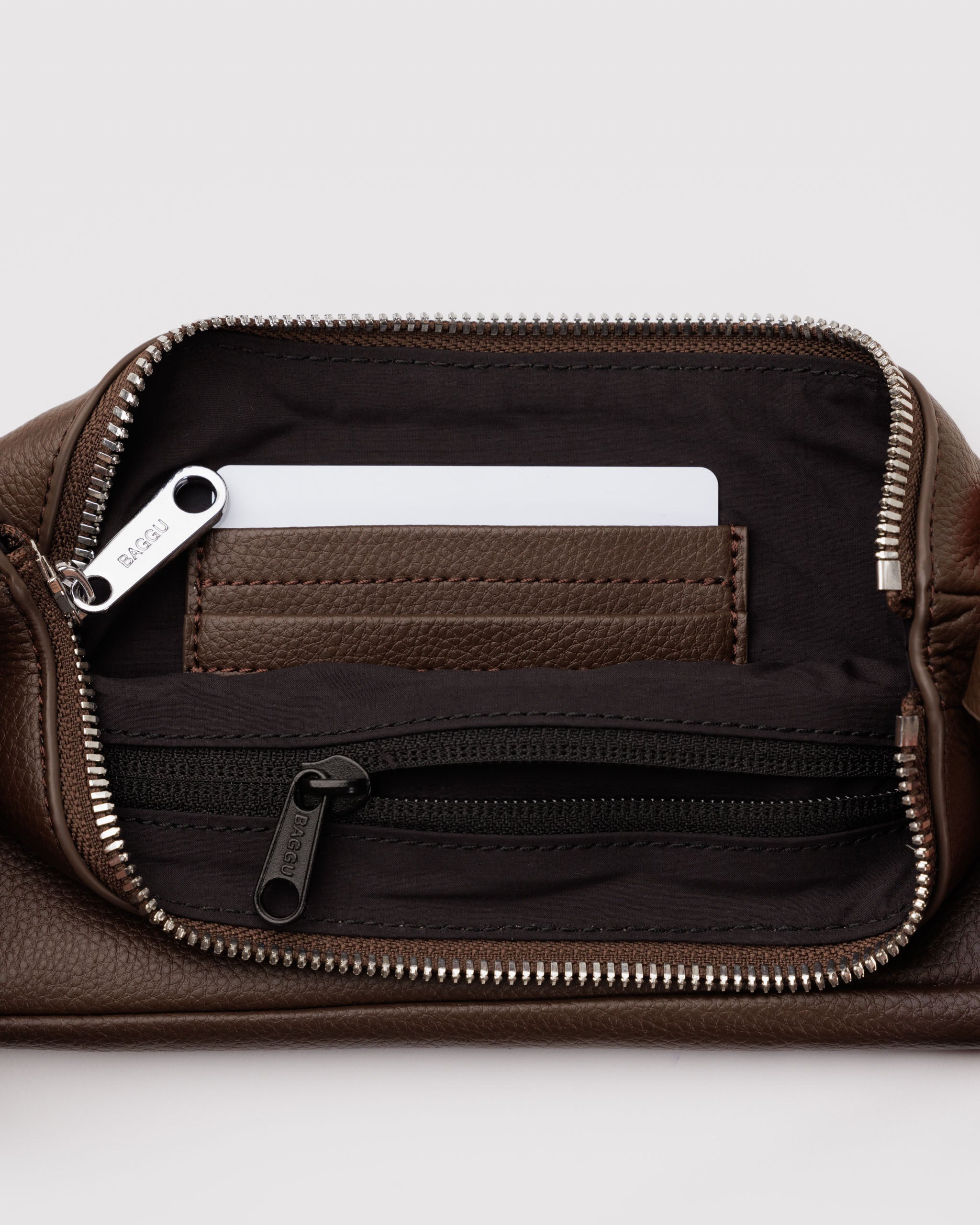 Brown leather bag with metal zipper open showing internal brown lining with zip pocket and brown leather card slots.