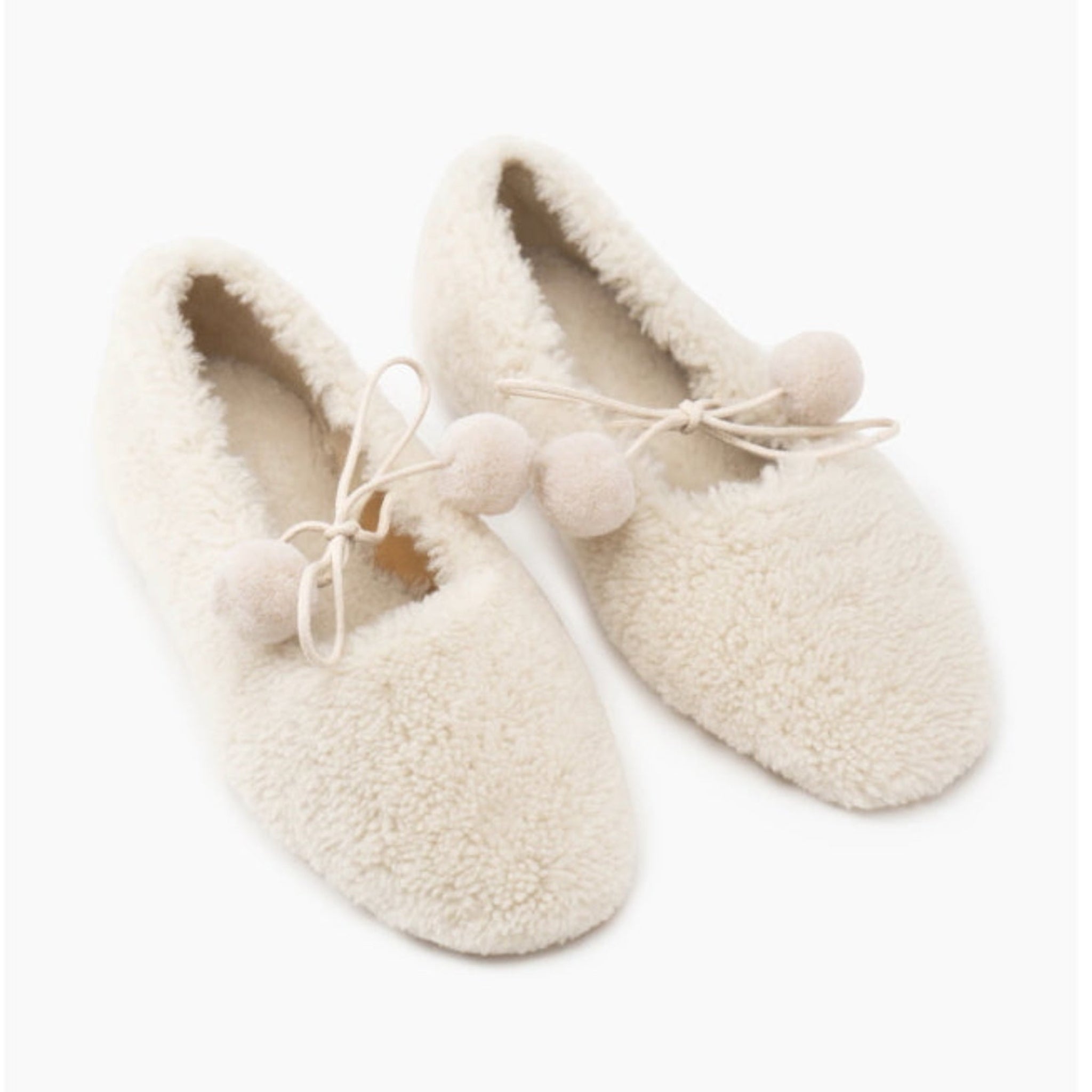 Pair of cream-coloured sheepskin slippers with pom-pom ties