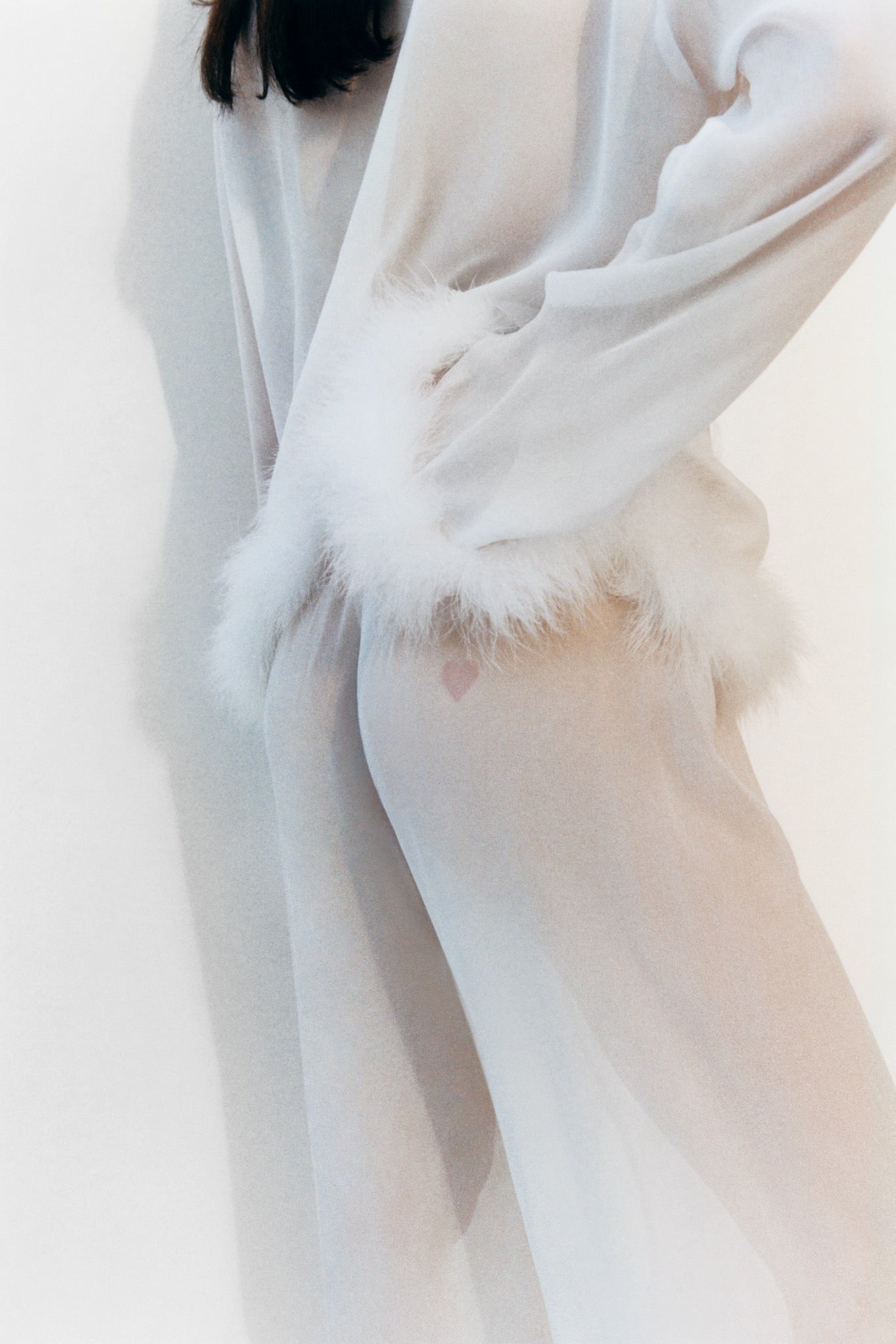 back-of-woman-wearing-afrodita-lounge-pants-and-shirt-set-in-white-showing-heart-shape-detail-on-pants