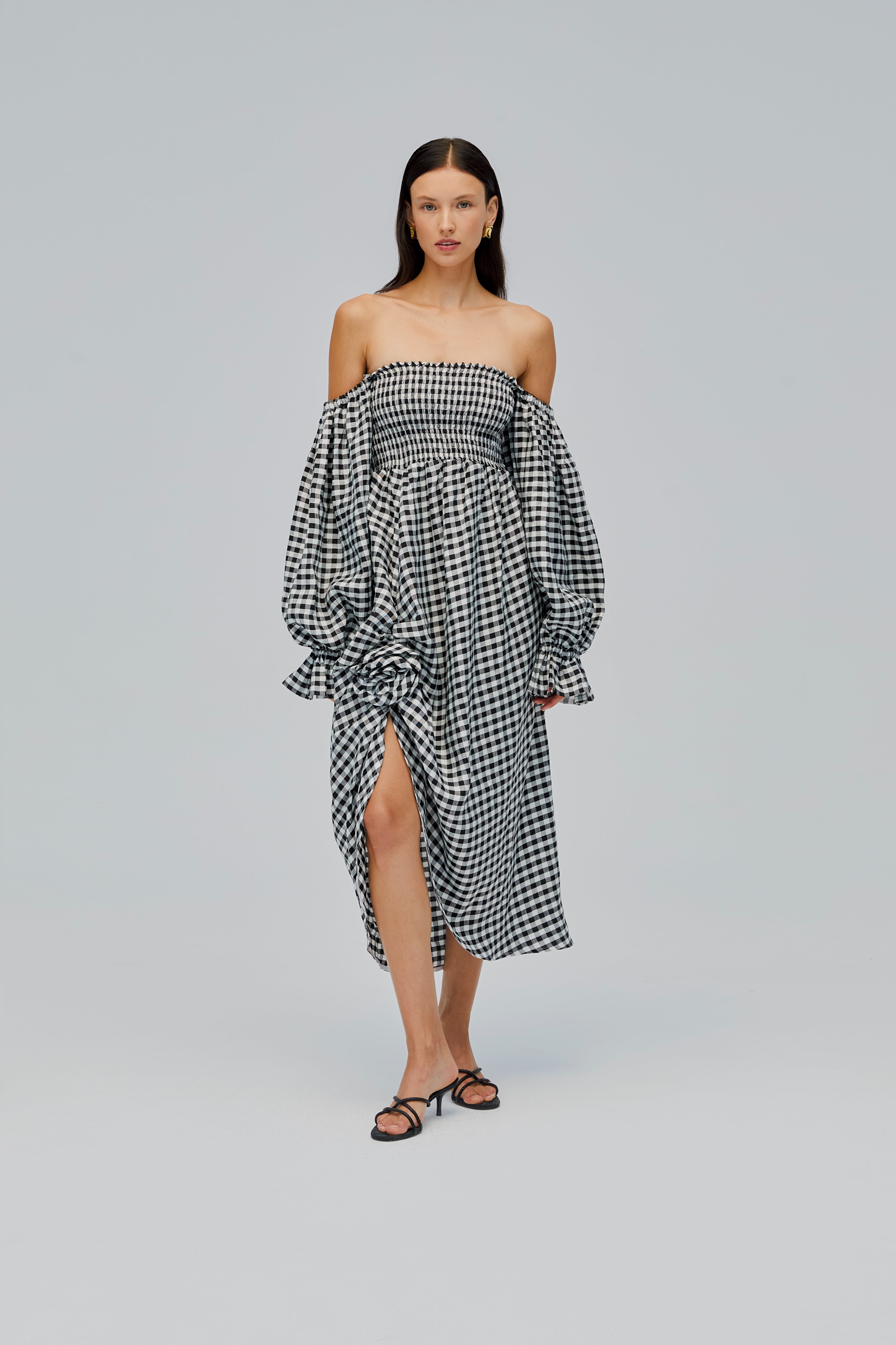 woman-wearing-black-gingham-off-shoulder-dress-with-rose-detail-long-sleeves-and-front-split