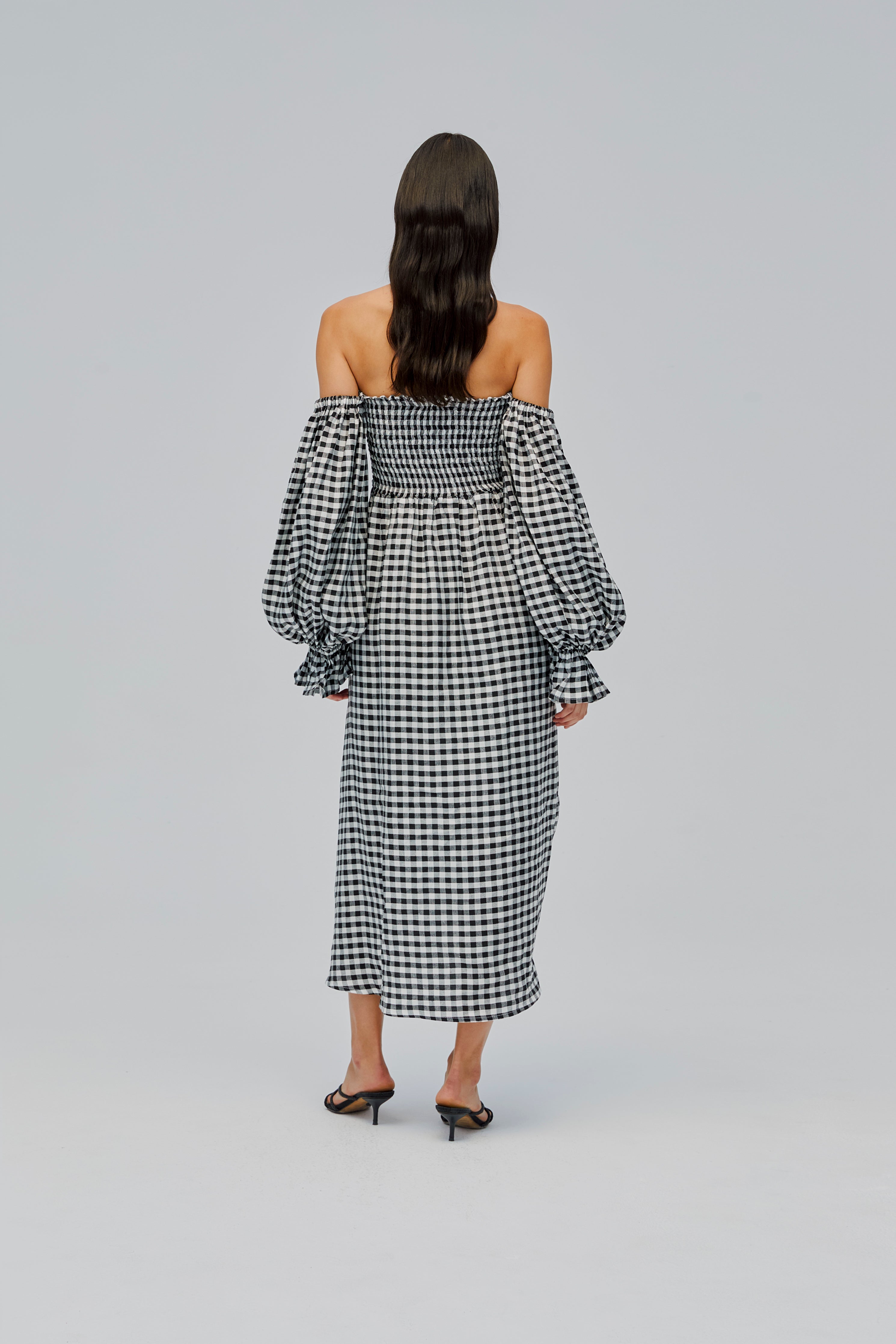 back-of-woman-wearing-black-gingham-off-shoulder-dress-smocked-bodice-long-sleeves