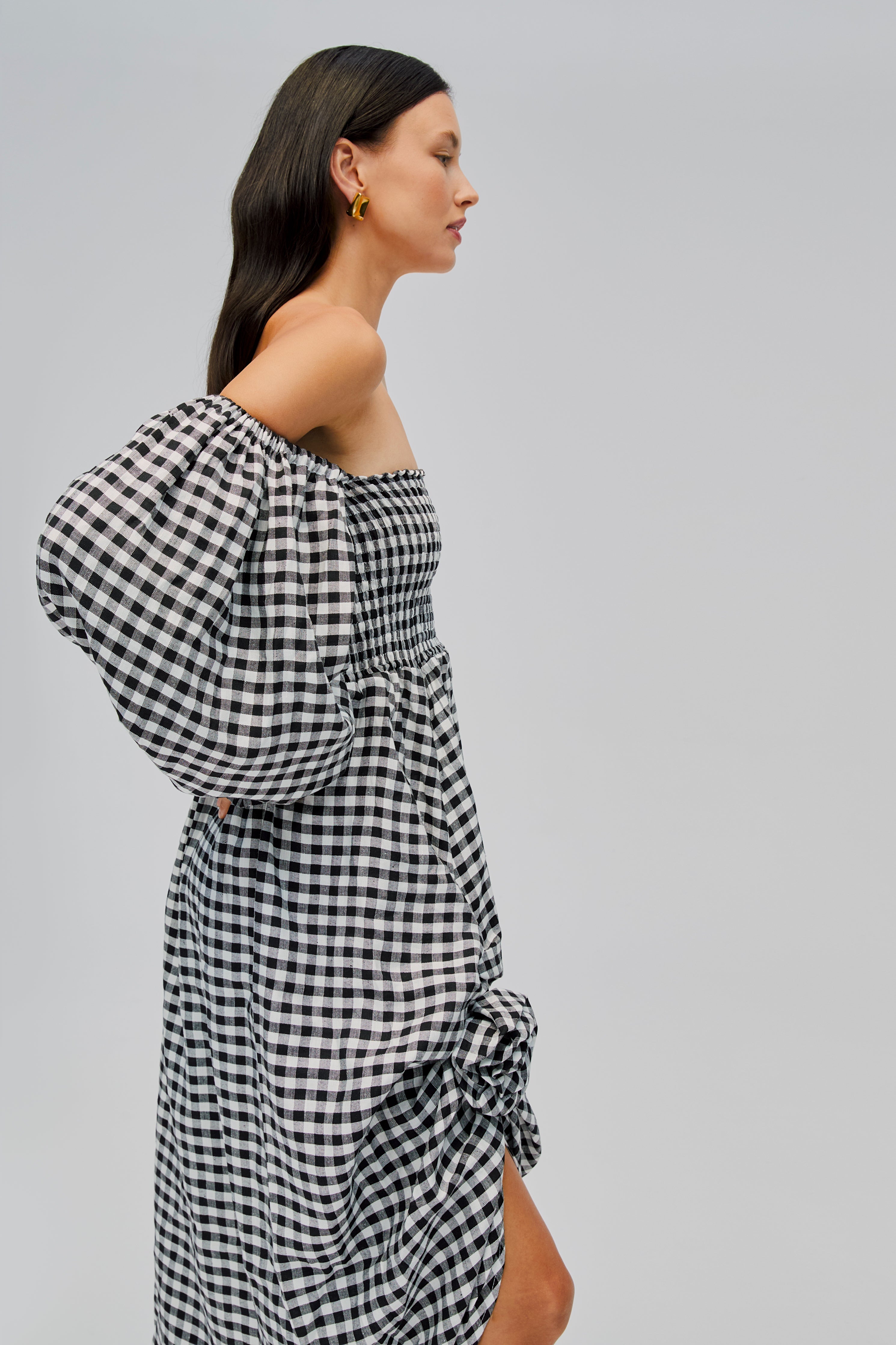 side-detail-of-woman-wearing-black-ginham-off-shoulder-dress-with-rose-detail-front-split